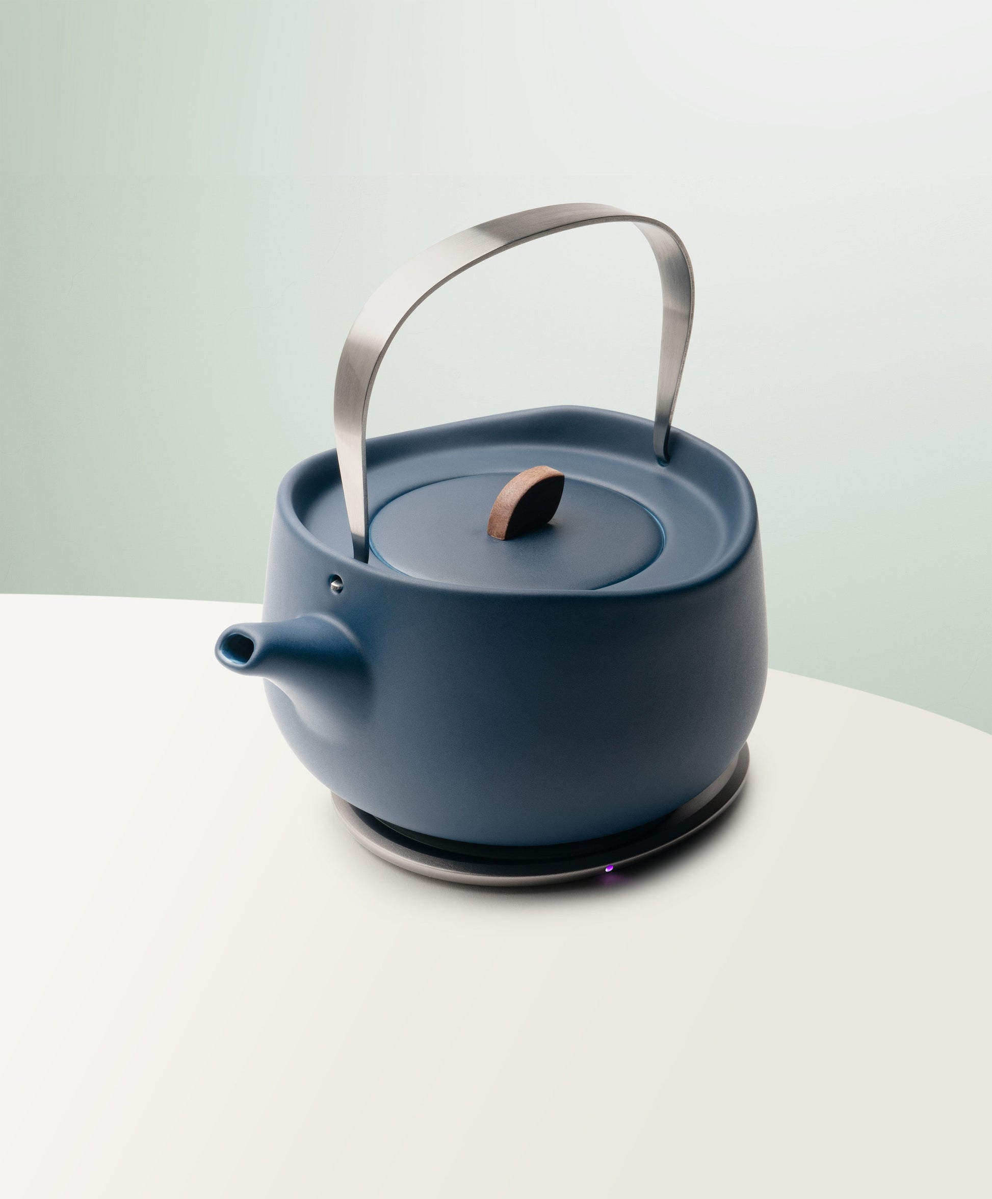 Leiph Self-Heating Ceramic Teapot Set 20 fl oz / 600 mL in Deep Navy angled top-side view on OHOM Charging Pad 3