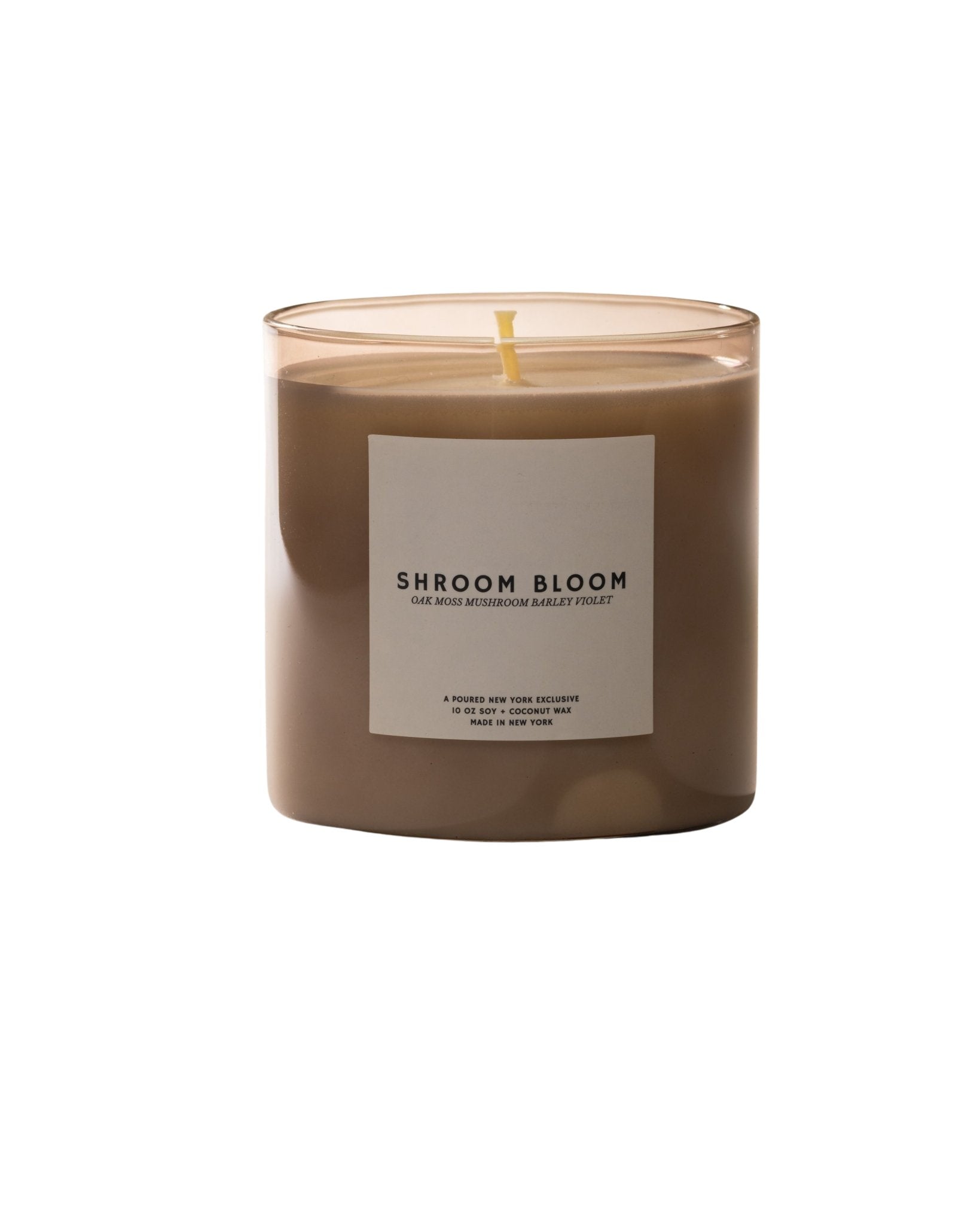Candle labeled 'Shroom Bloom' with a box in the background on a light beige background