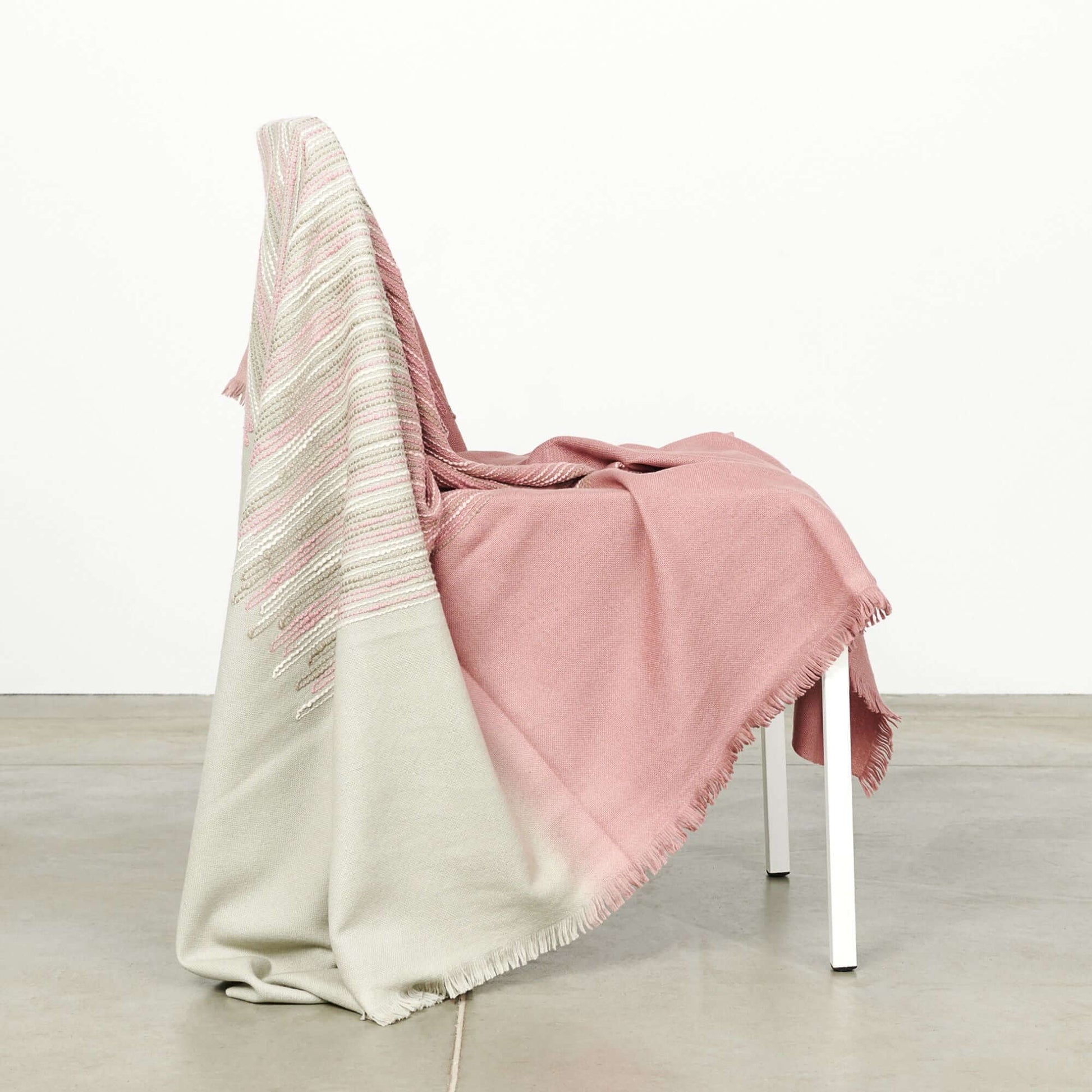 Chive Pink Green Ombre Handloom Merino Throw draped over a chair, showcasing its unique color and texture.
