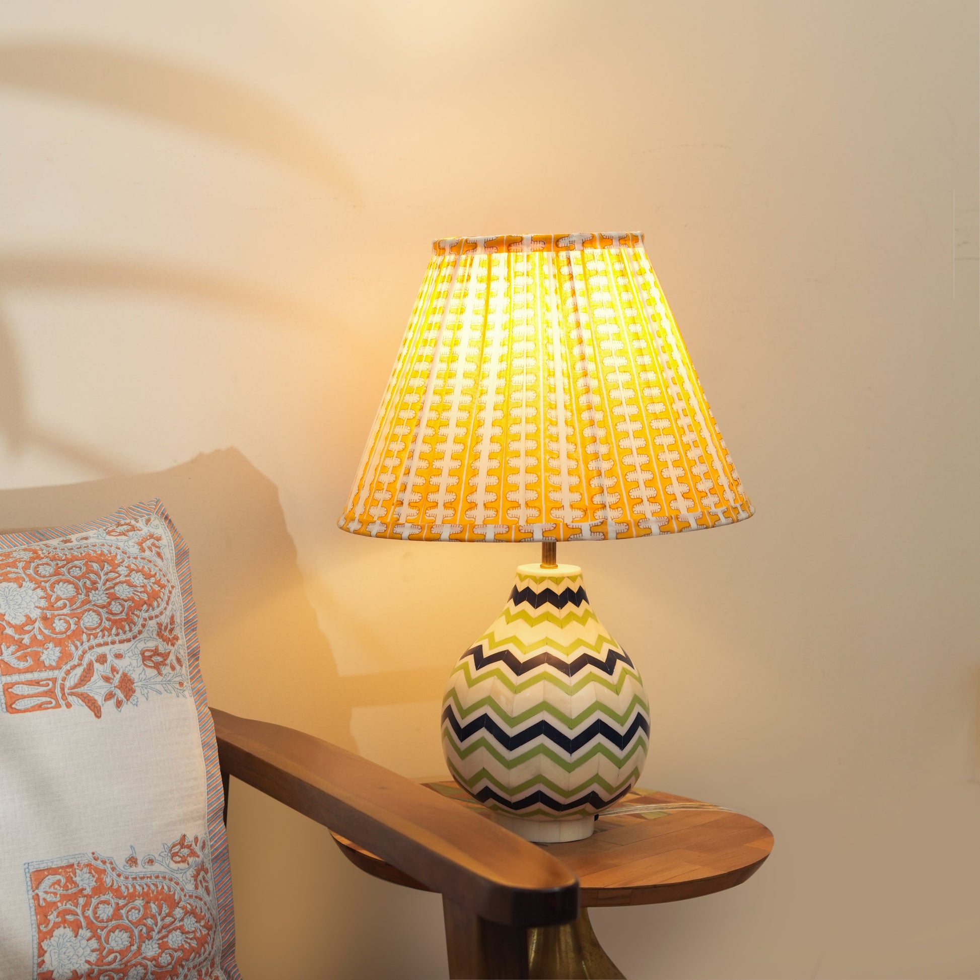 Lit Chevron table lamp casting a warm glow in a living room, highlighting the intricate bone and resin textures.
