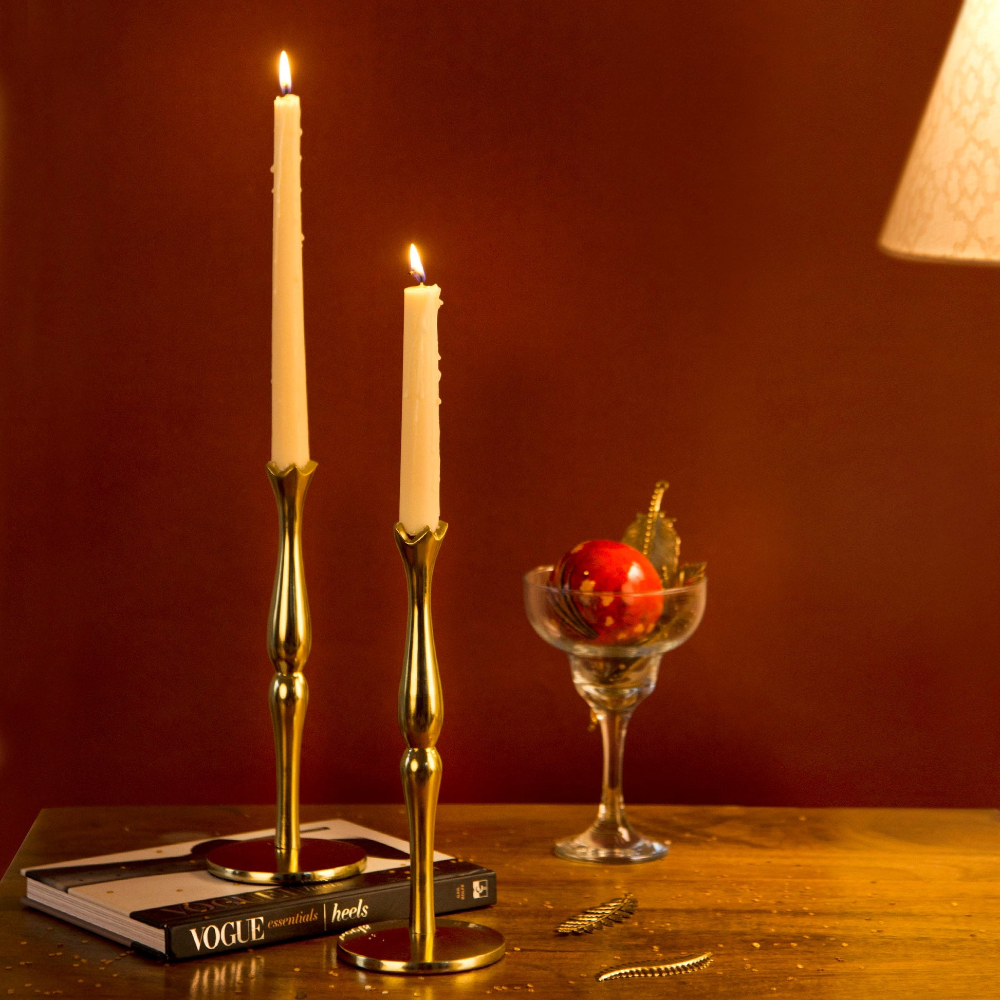Hand-finished solid brass candle holders featuring a warm metallic glow and a weighted round base.