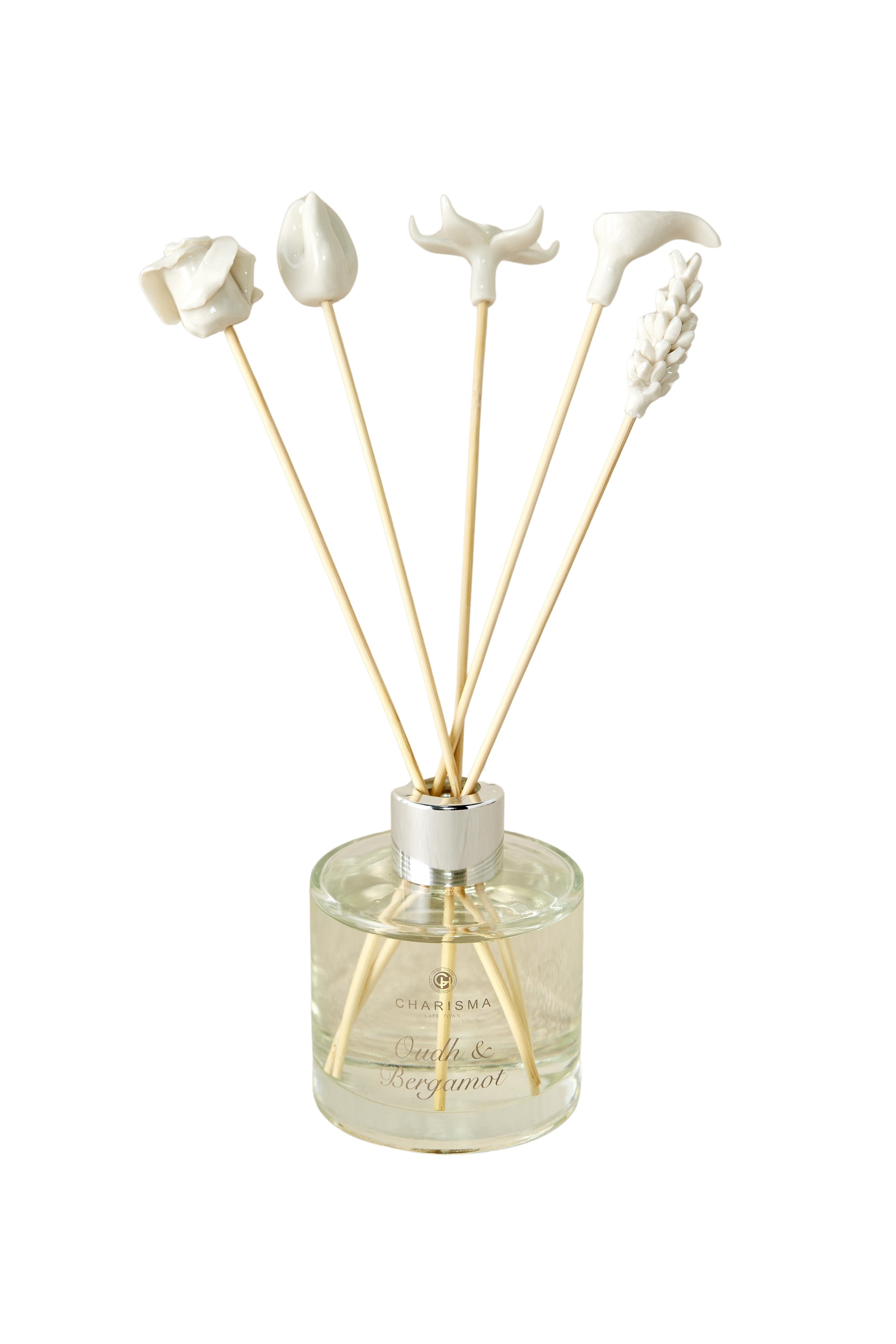 A set of white porcelain floral diffuser sticks placed in a clear glass container, with a beige background.