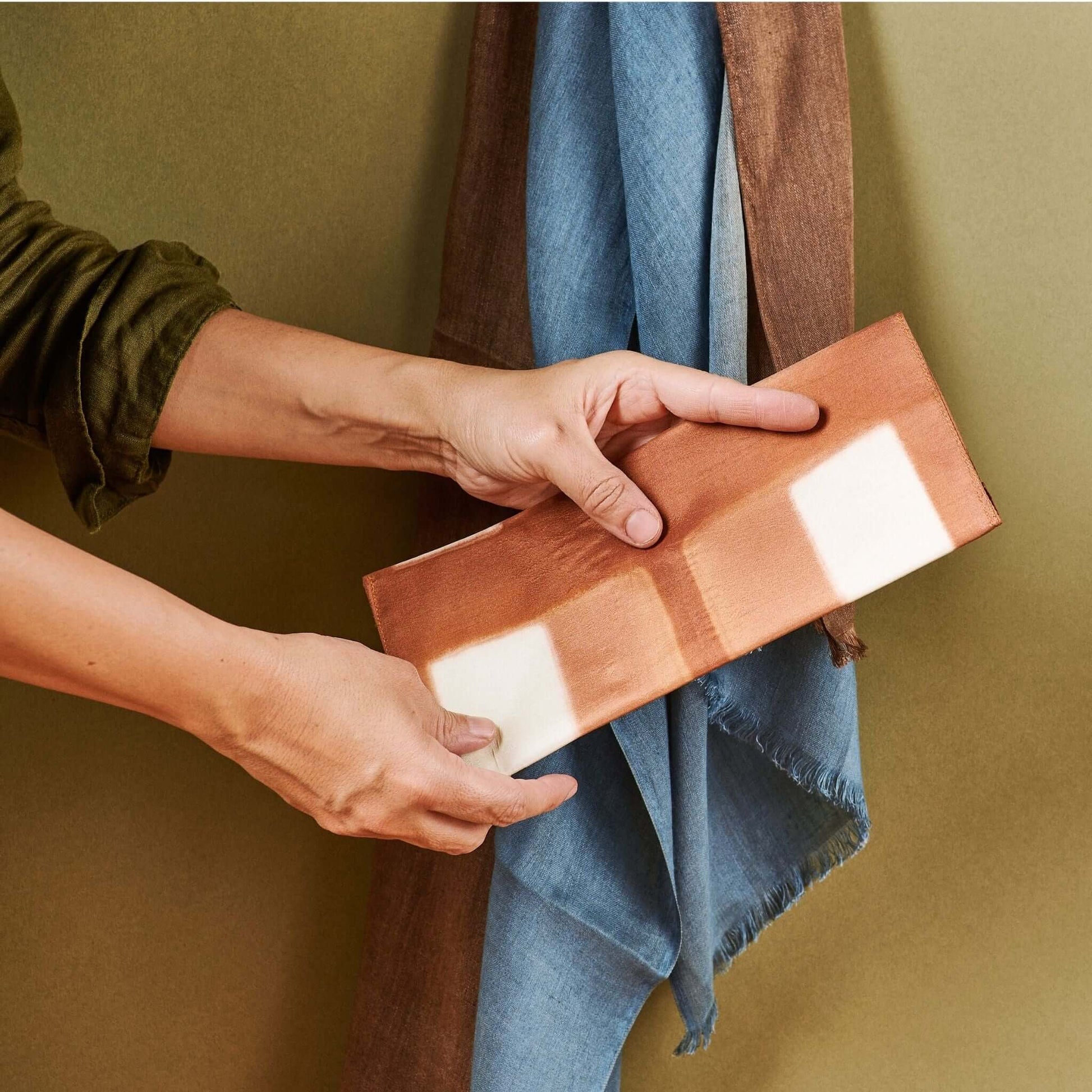 Melo Gold Mulberry Silk Shibori Hand Crafted Envelope Pouch being held by a person, showcasing its unique design.