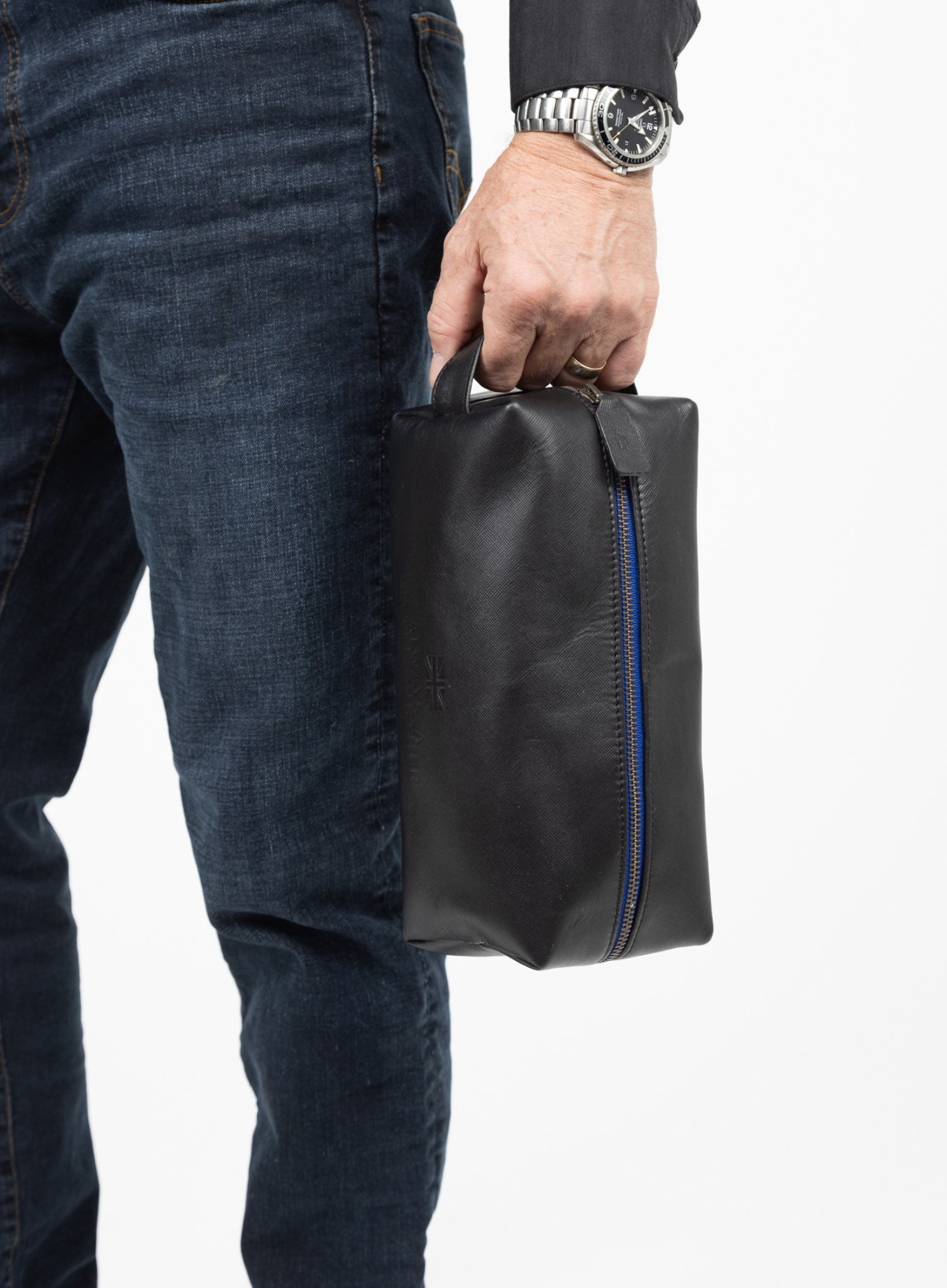 iron tight toiletry bag in black showcasing blue stitching and model using handle to hold washbag.