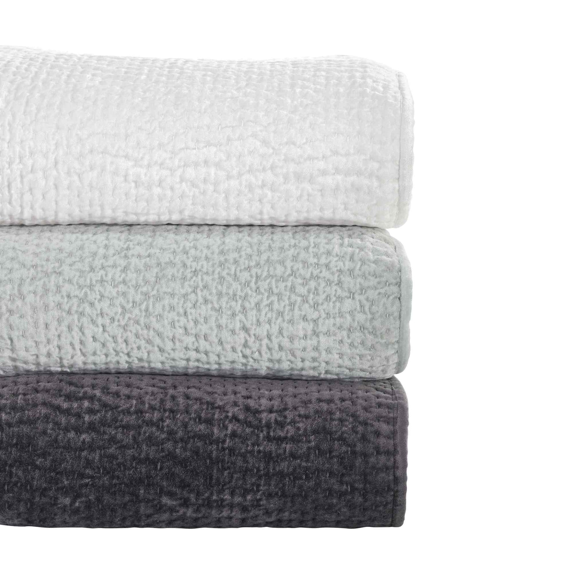 CL-184-9496-LOT1_6|Stack of three textured coverlets in white, sage green, and charcoal grey, showcasing versatile bedroom options.