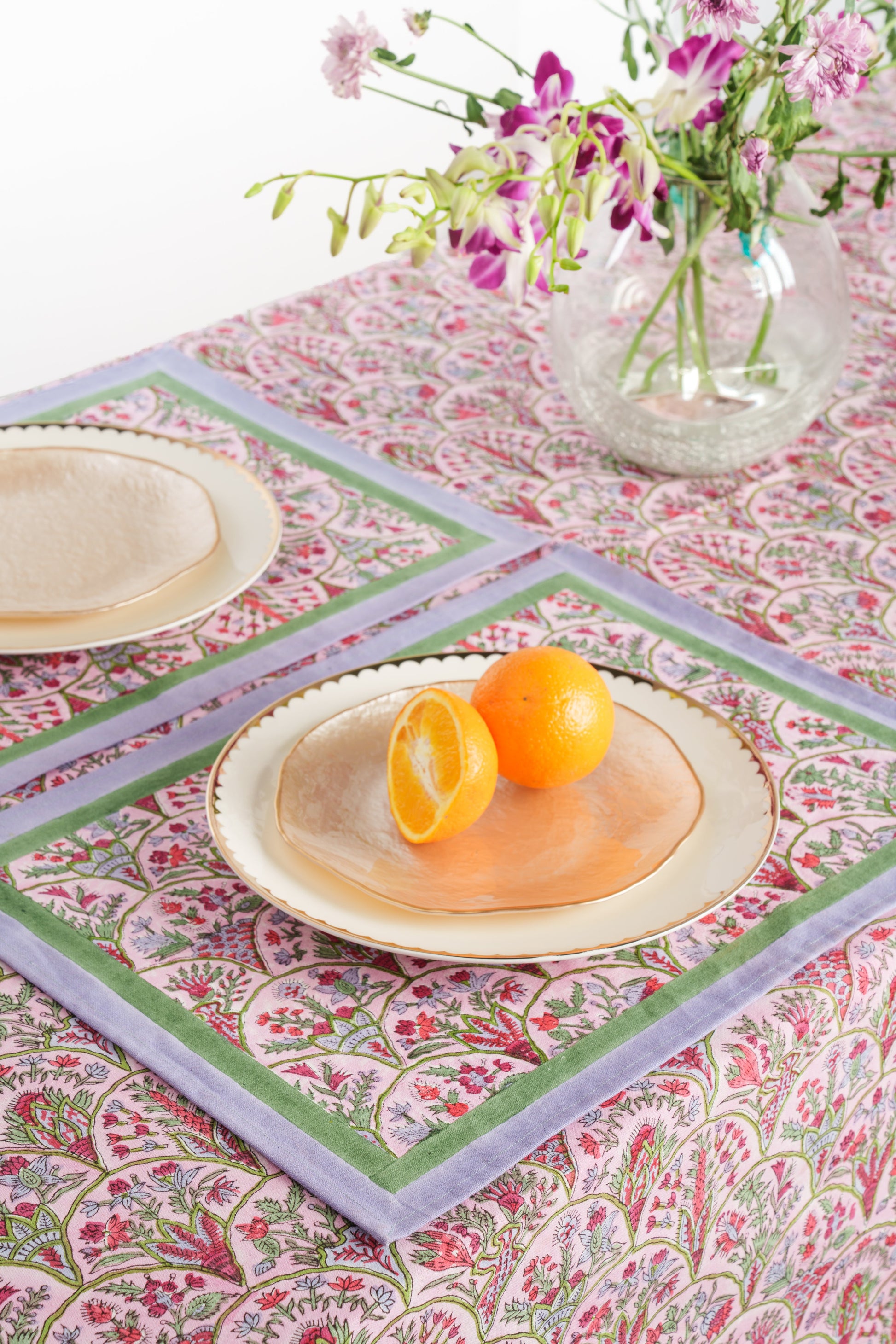 Pink arch blockprint placemat with orange slices on gold plate