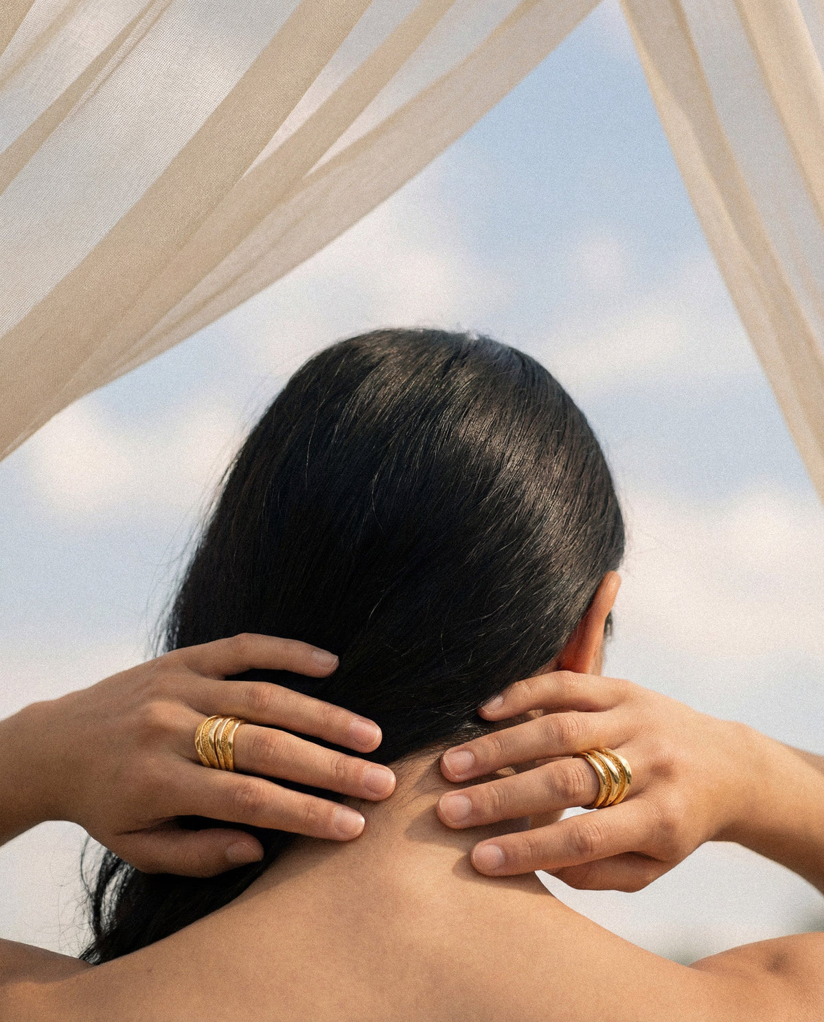 Hand wearing stacked Currents Trace rings in gold