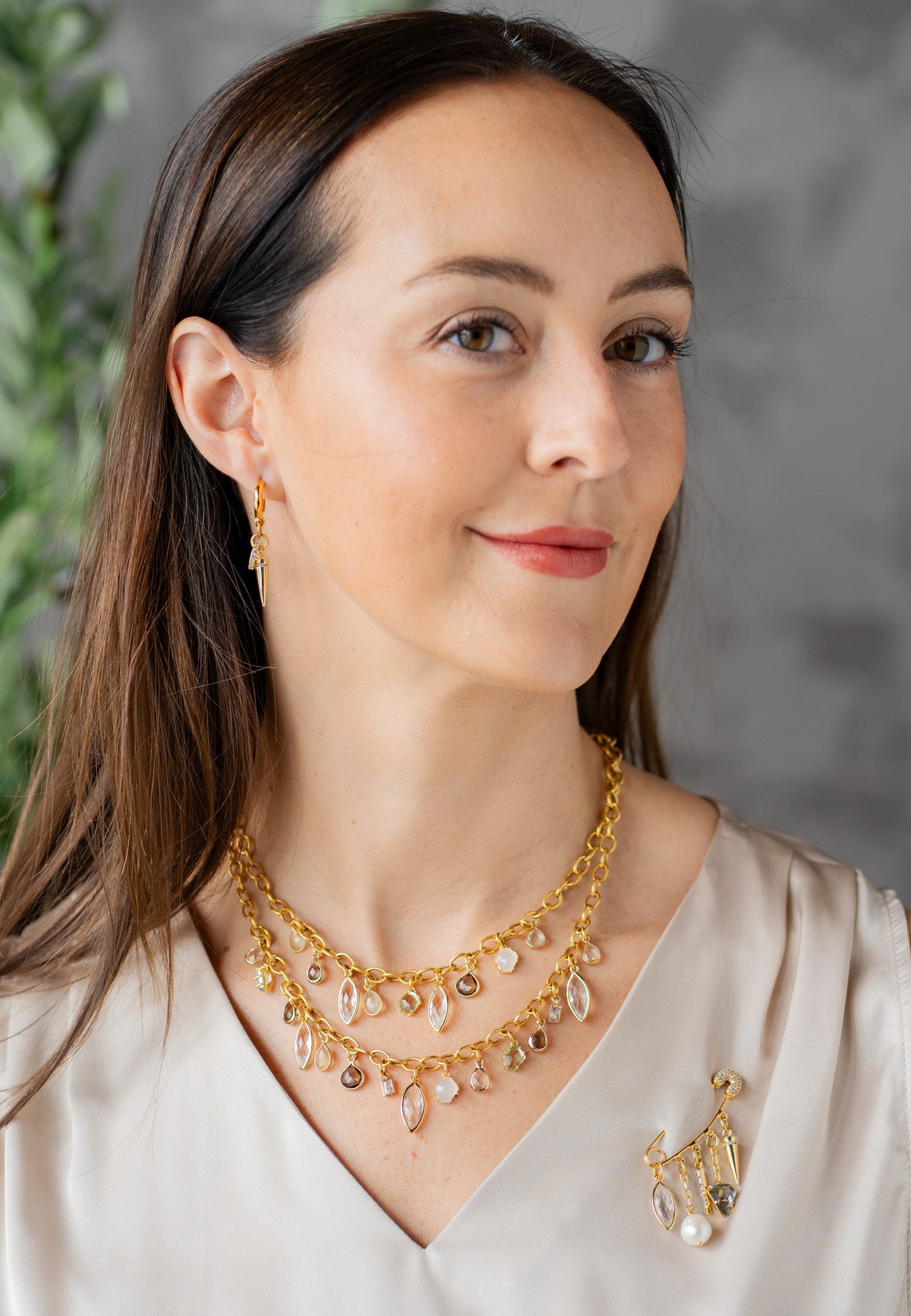 Gold brooch with dangling charms including marquis crystal, pearl, pave spike, smoky quartz triangle, and gold spike