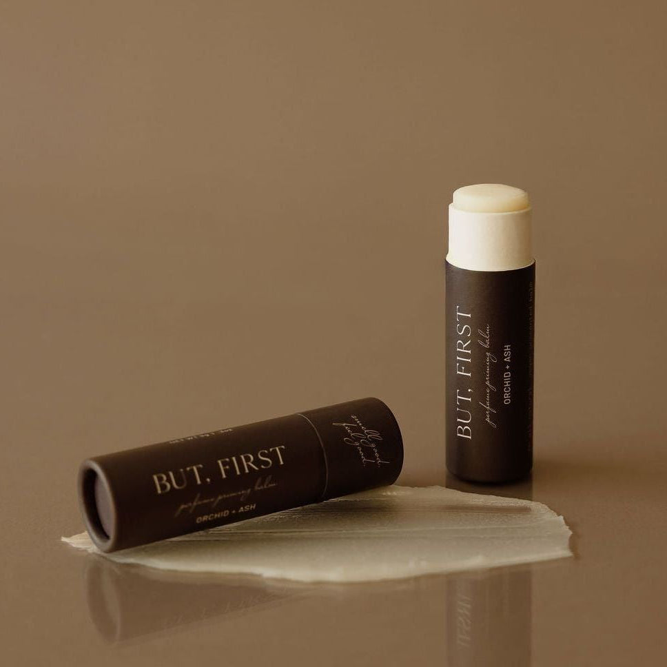 BUT FIRST lip balm and packaging on a brown background