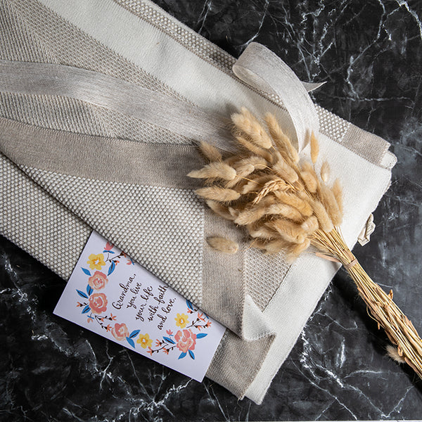 Decorative beige cotton throw with a dried plant and greetings card for Grandma.