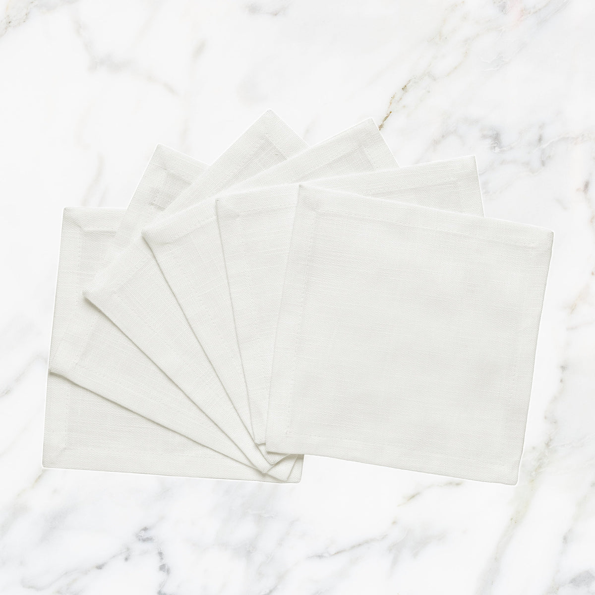 CNP-4908-66_1|Set of fanned white linen napkins displayed on a pristine white marble background for elegant table settings.