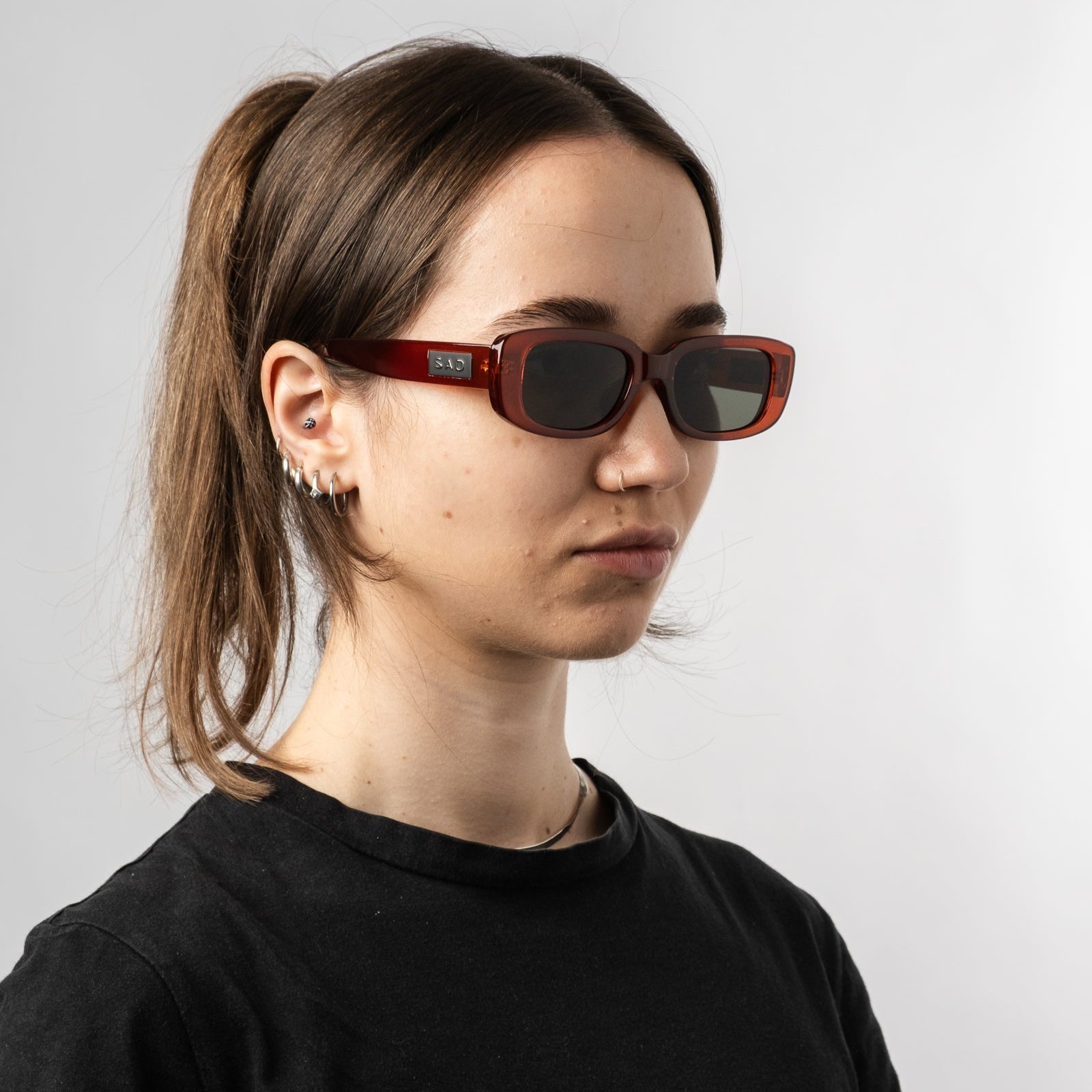 Female wearing Sad Eyewear Bouquet rectangle sunglasses in blood red with black tinted lenses