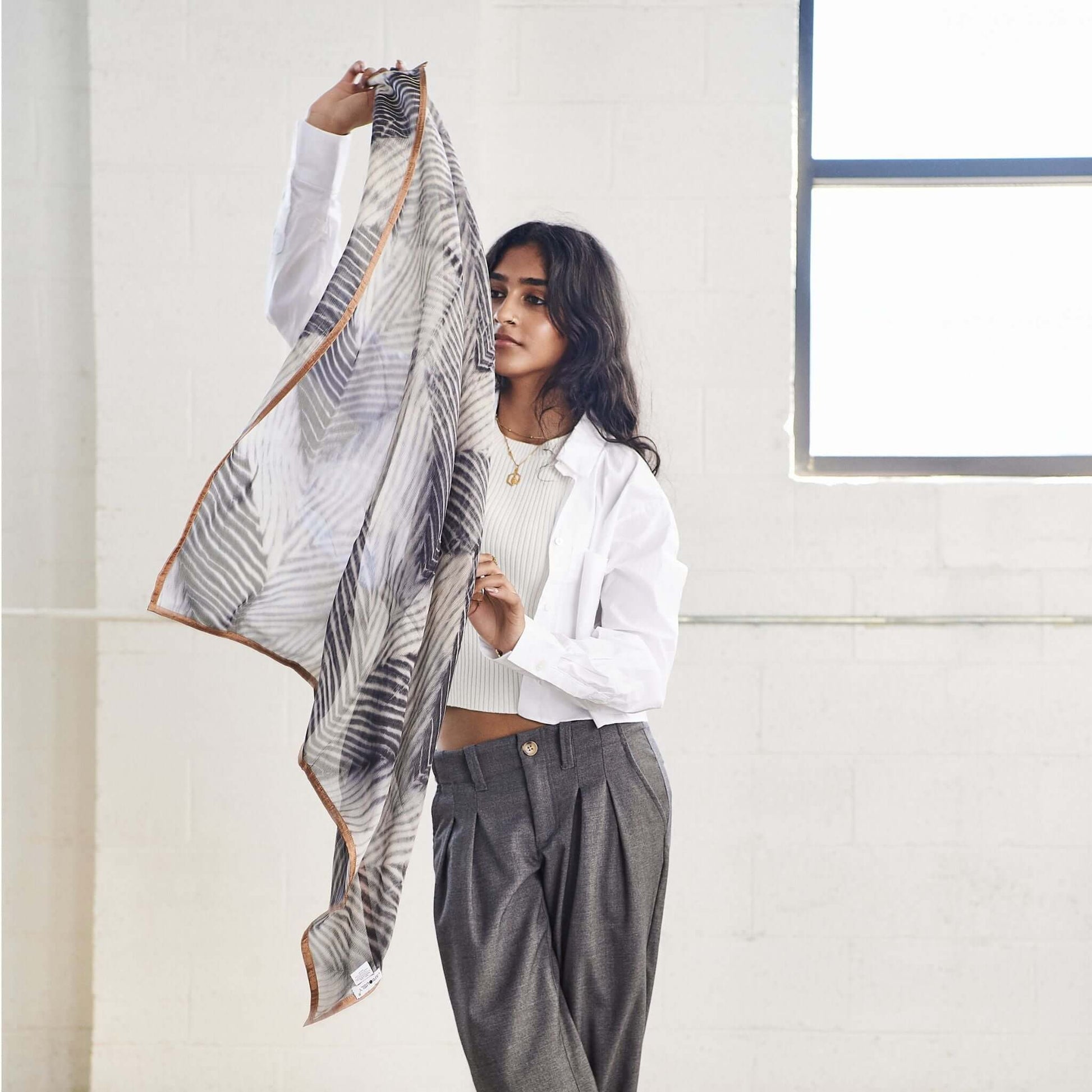 Woman showcasing a Samu Black hand crafted chiffon square scarf, emphasizing its elegant design and versatility in fashion.