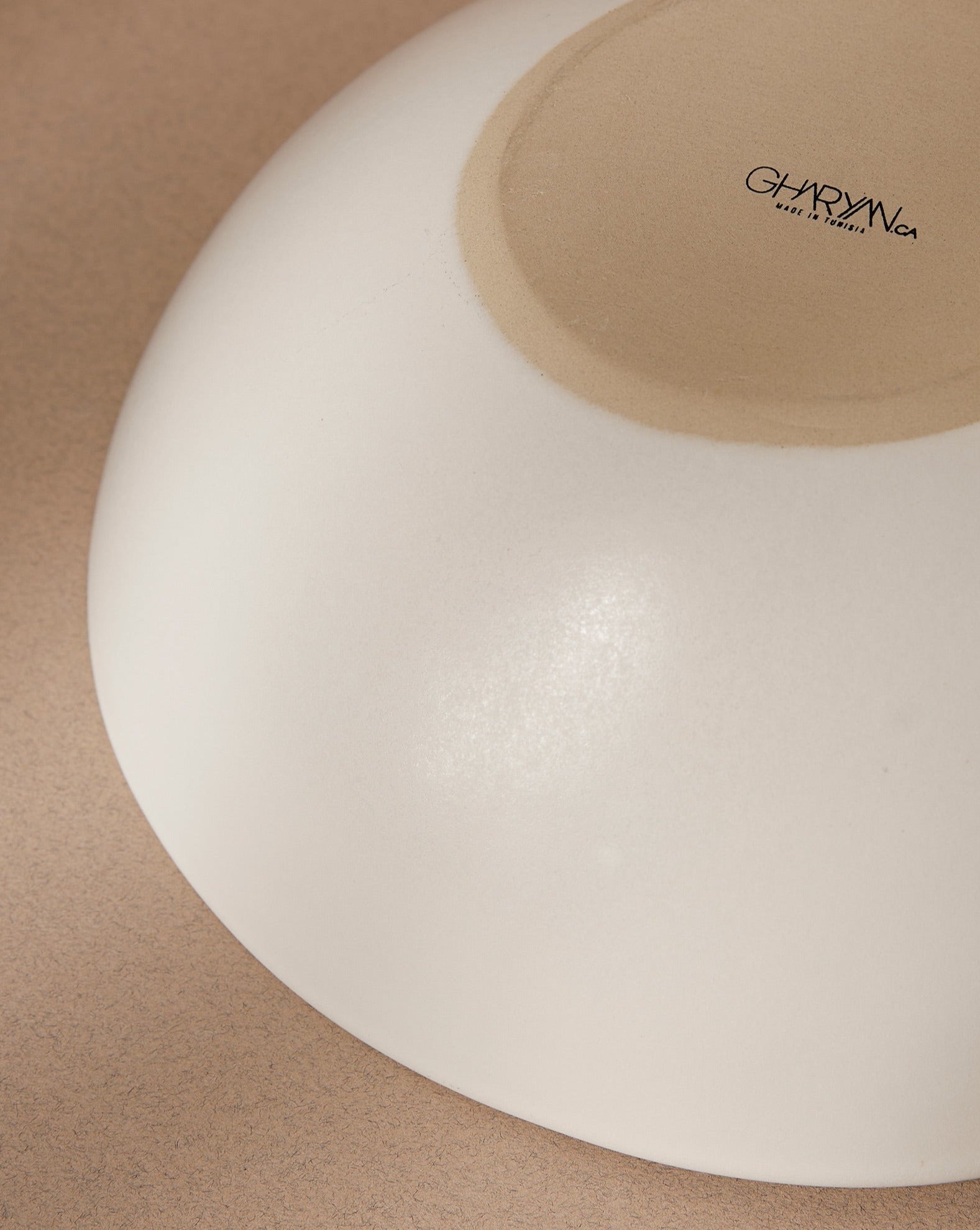 Upside-down white stoneware serving bowl with the 'GHARYAN' logo visible, displayed against a cream background.