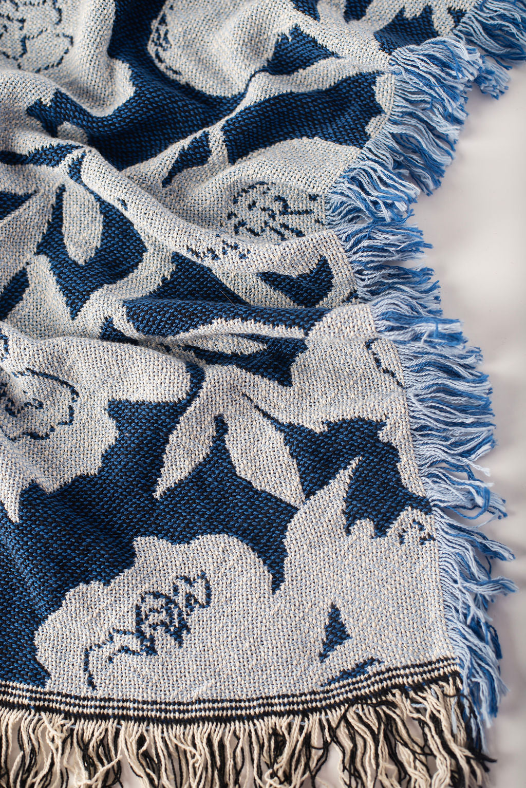 Folded blue and light blue floral blanket from the angled sideview on a light background