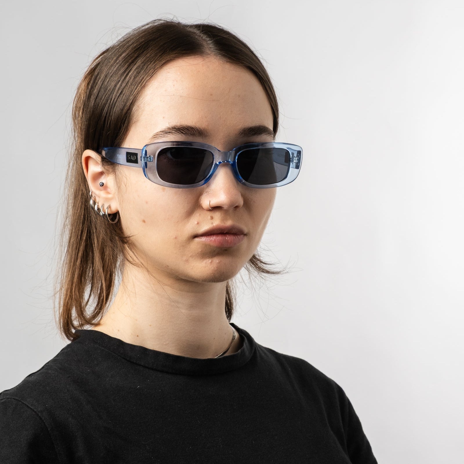 Female wearing Sad Eyewear Bouquet rectangle sunglasses in arctic blue with black tinted lenses