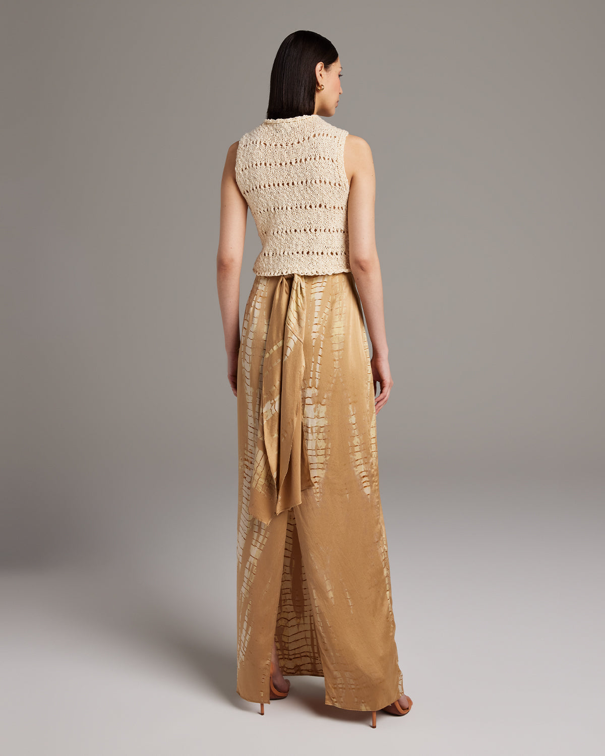 Model wearing a hand-knit Flammé Knit Crop Top with a back view, paired with a flowy skirt.