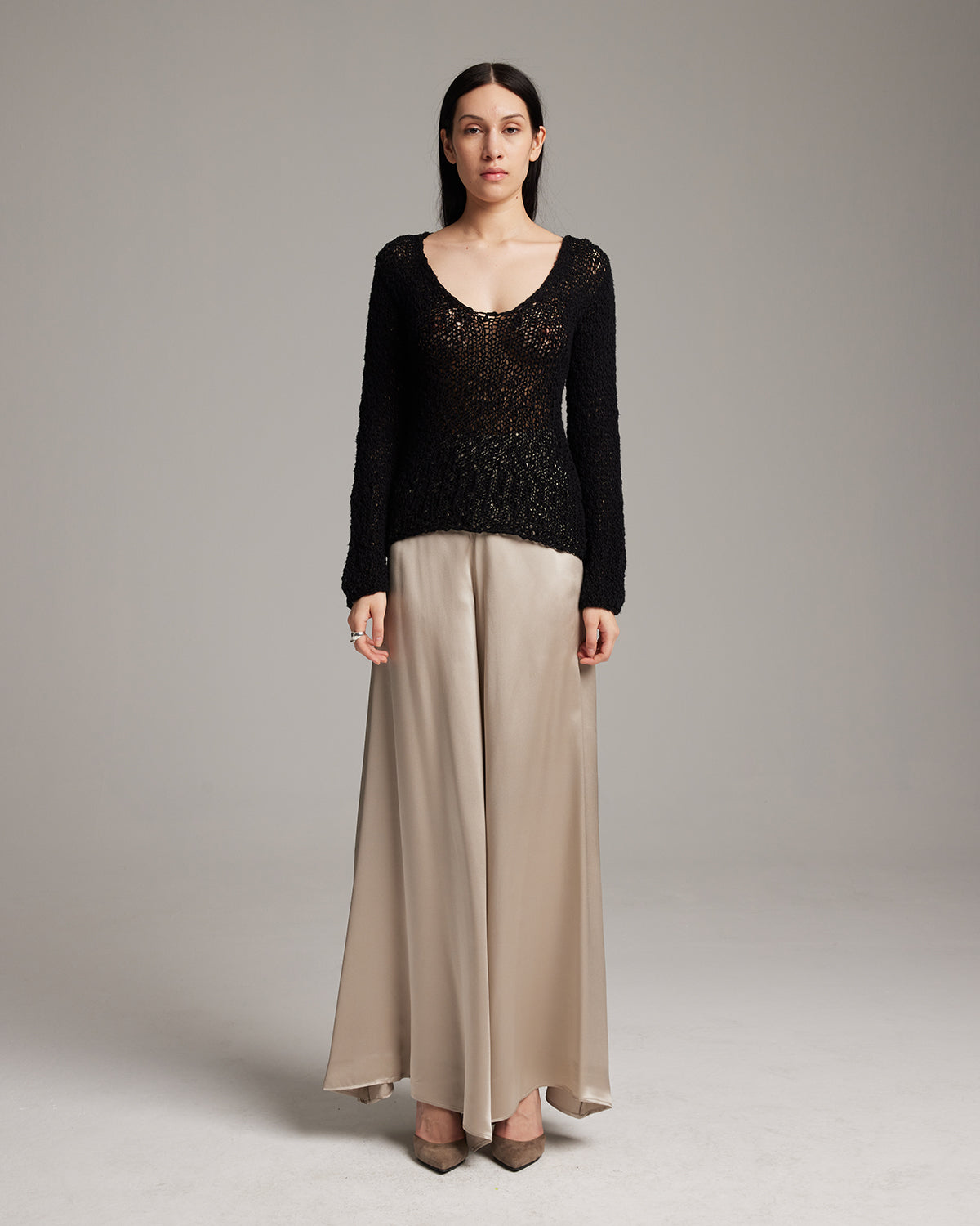 Model wearing a black sweater and beige silk palazzo pants