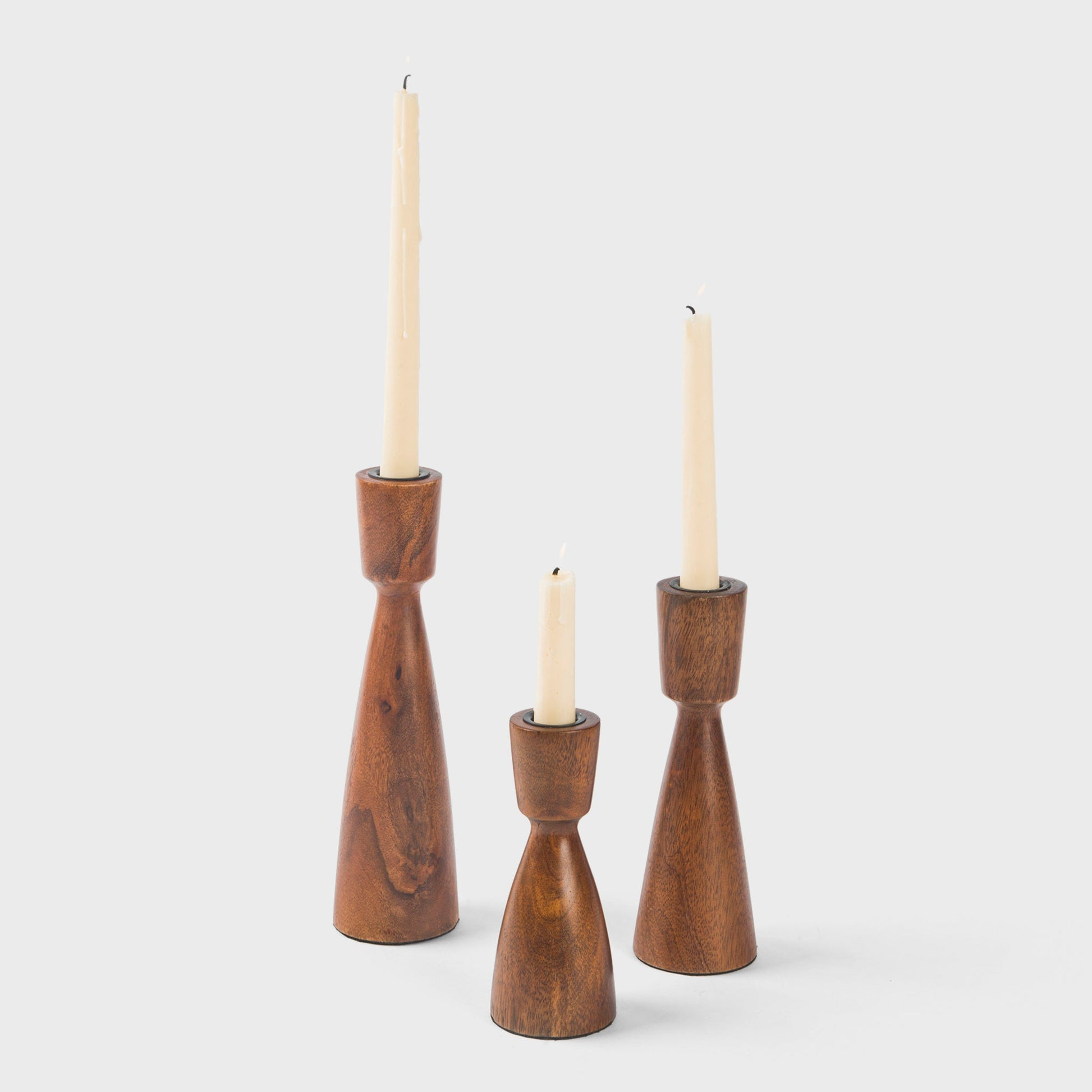 Trio of Hearth mango wood taper candlestick holders in varying heights featuring natural wood grain and slender tapered silhouettes.