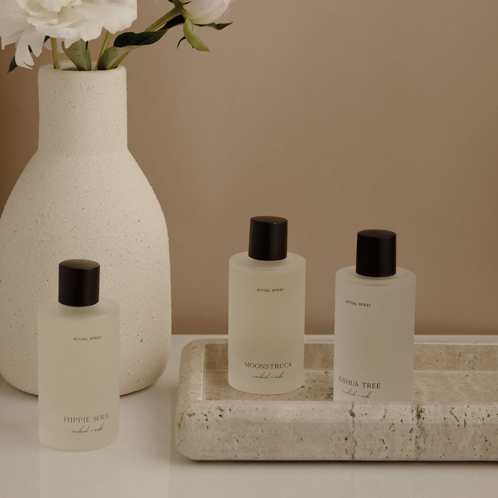 Set of skincare products on a tray with a vase of flowers on a neutral background