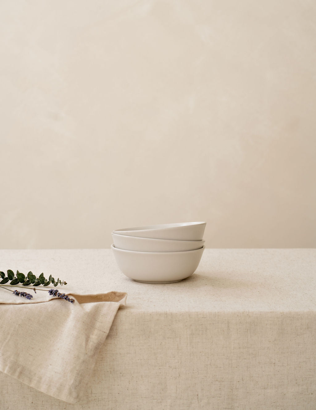 Stack of Bone ivory non-toxic ceramic bowls from Hamkke Home on a neutral tablecloth for product display.