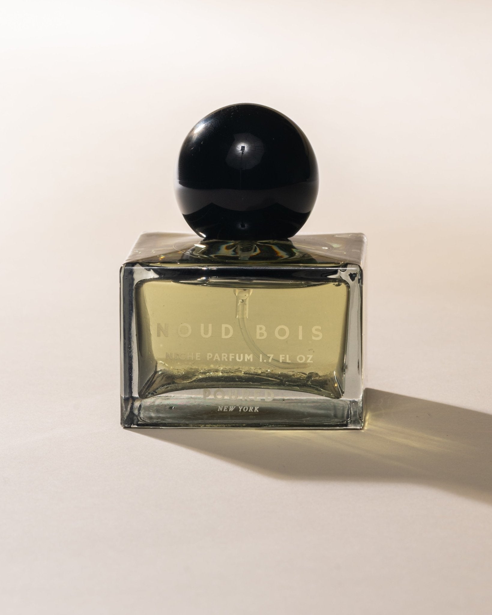 Poured New York 'Noud Bois' Niche Parfum square bottle with black circular cap on neutral background