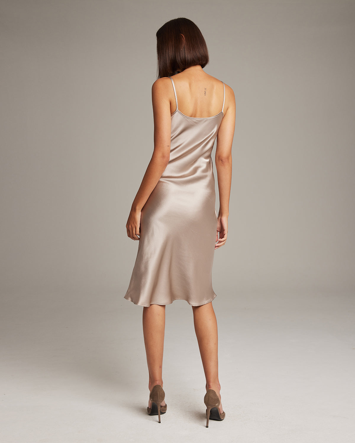 Back view of a Midi Slip Dress in a soft beige color, showcasing its elegant drape.