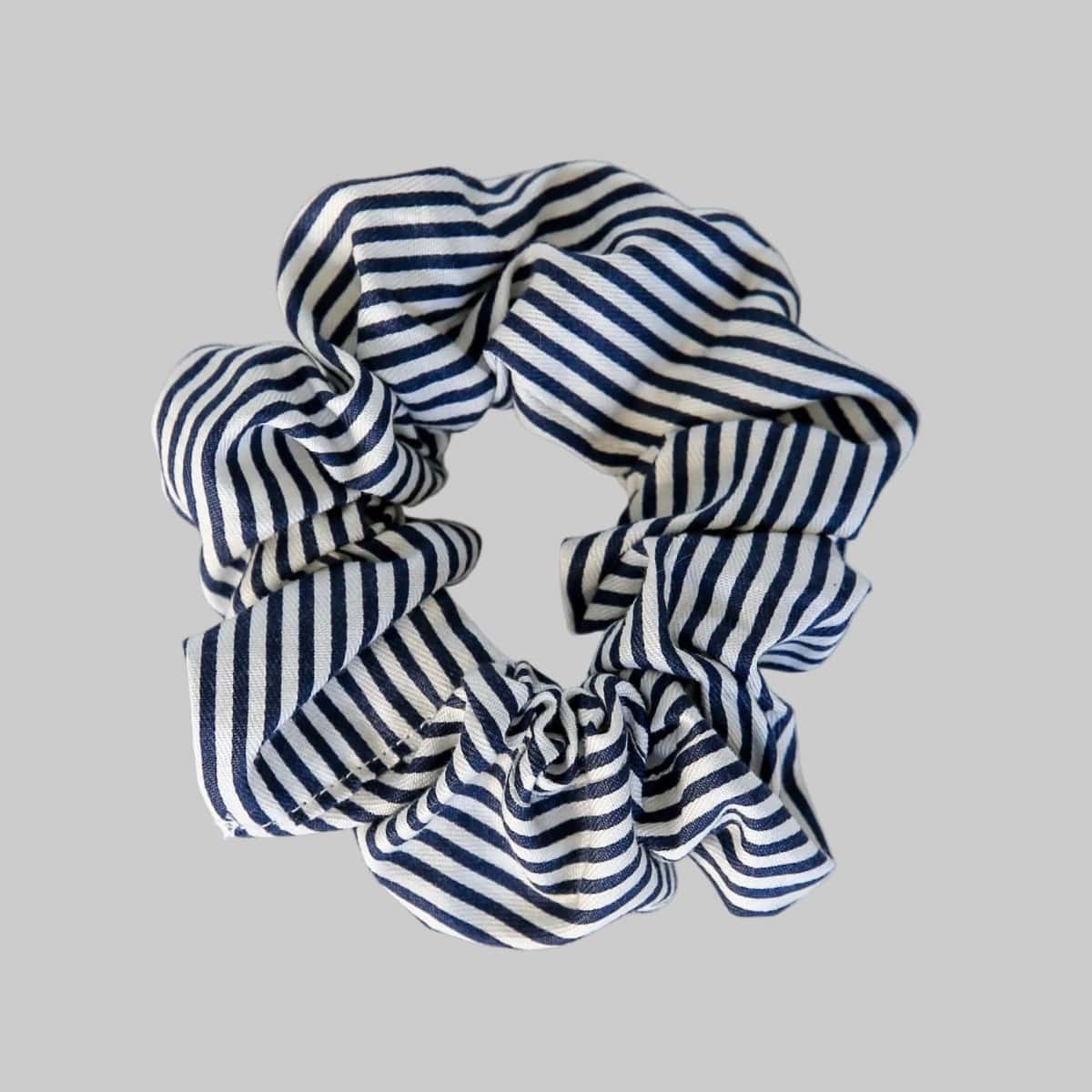 Navy and white striped scrunchie on a gray background