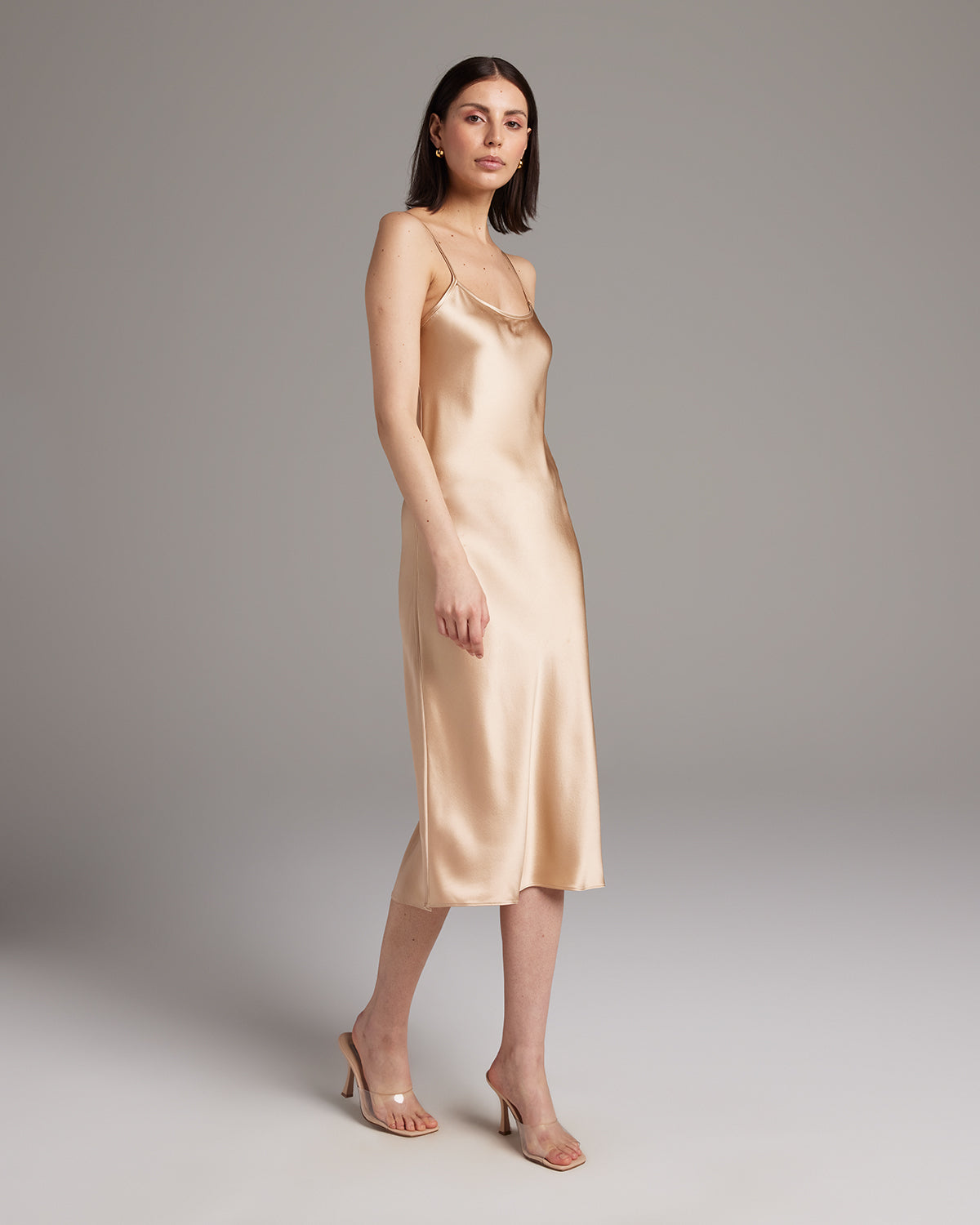 Model wearing a light beige satin Midi Slip Dress, showcasing its elegant drape.