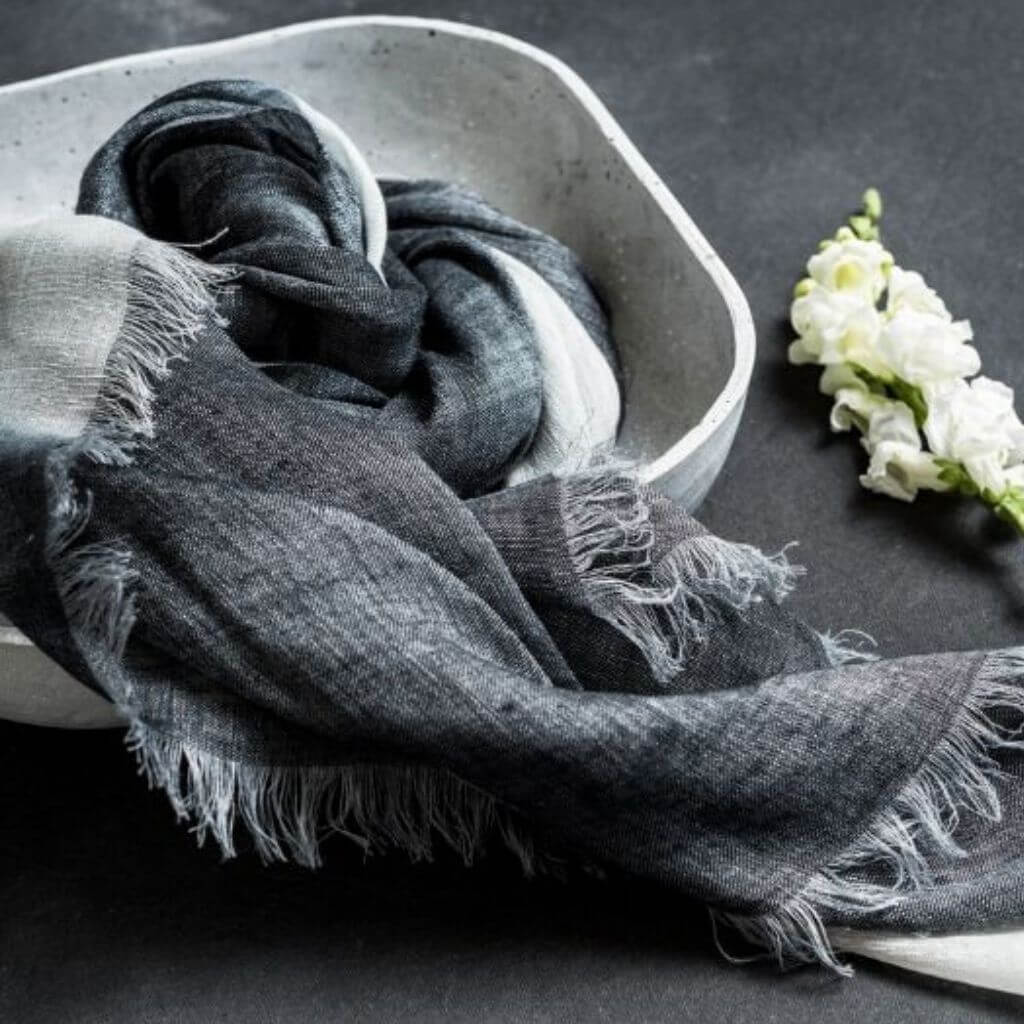 Granite Black White Ombre Linen Silk Handloom Scarf displayed in a bowl with a flower, showcasing its elegant texture and design.