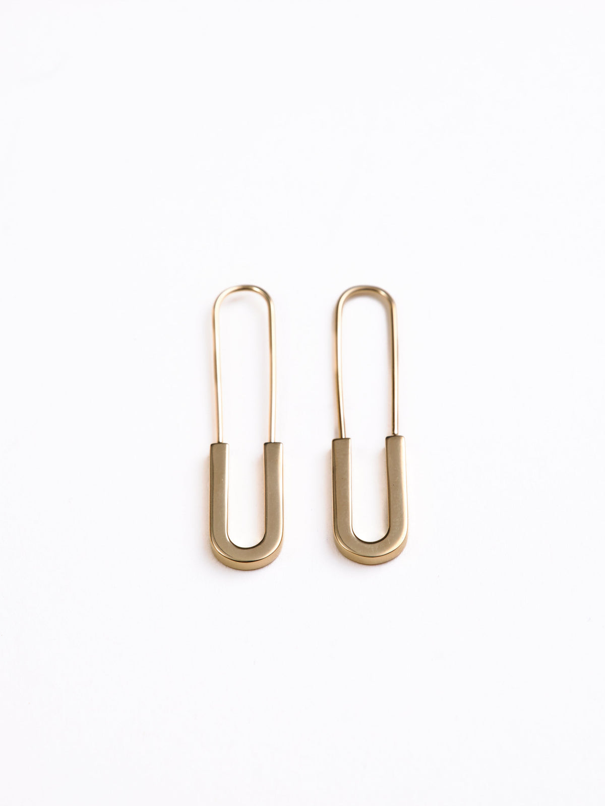 Gold safety pin earrings on a white background