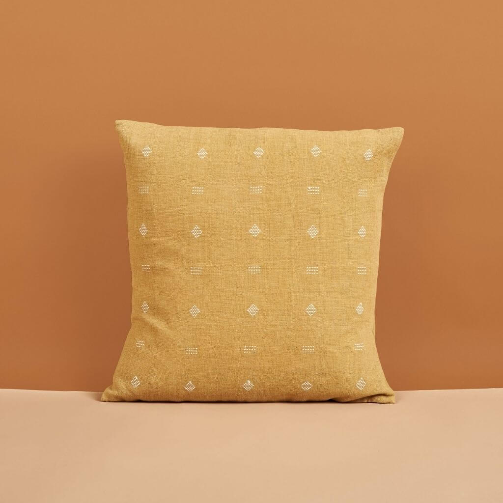 Nira Ochre Hand Spun Organic Cotton Handloom Pillow showcasing classic texture and design against a warm backdrop.