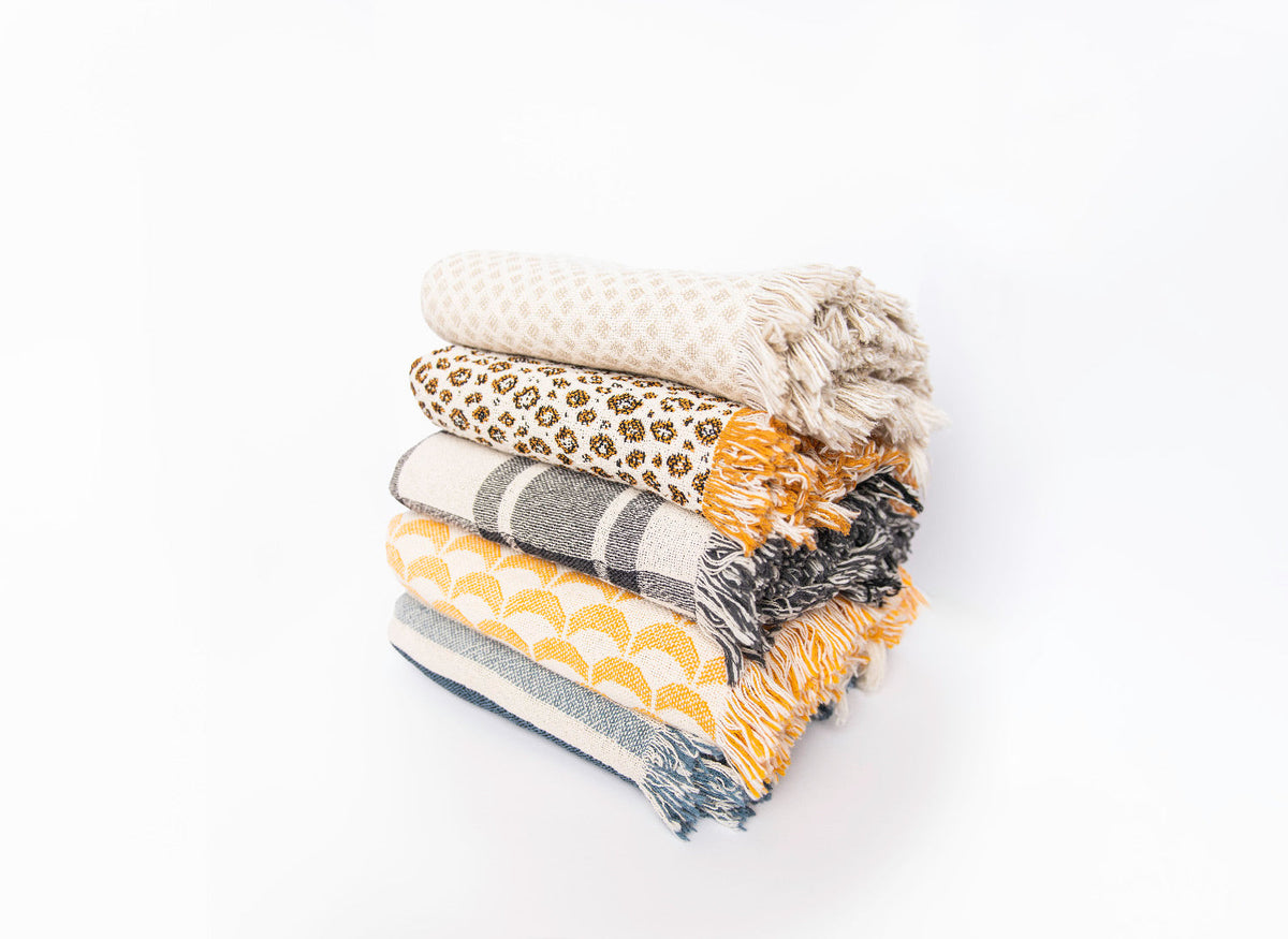 Angled stack of five artist-designed woven blankets including Sutton Delft