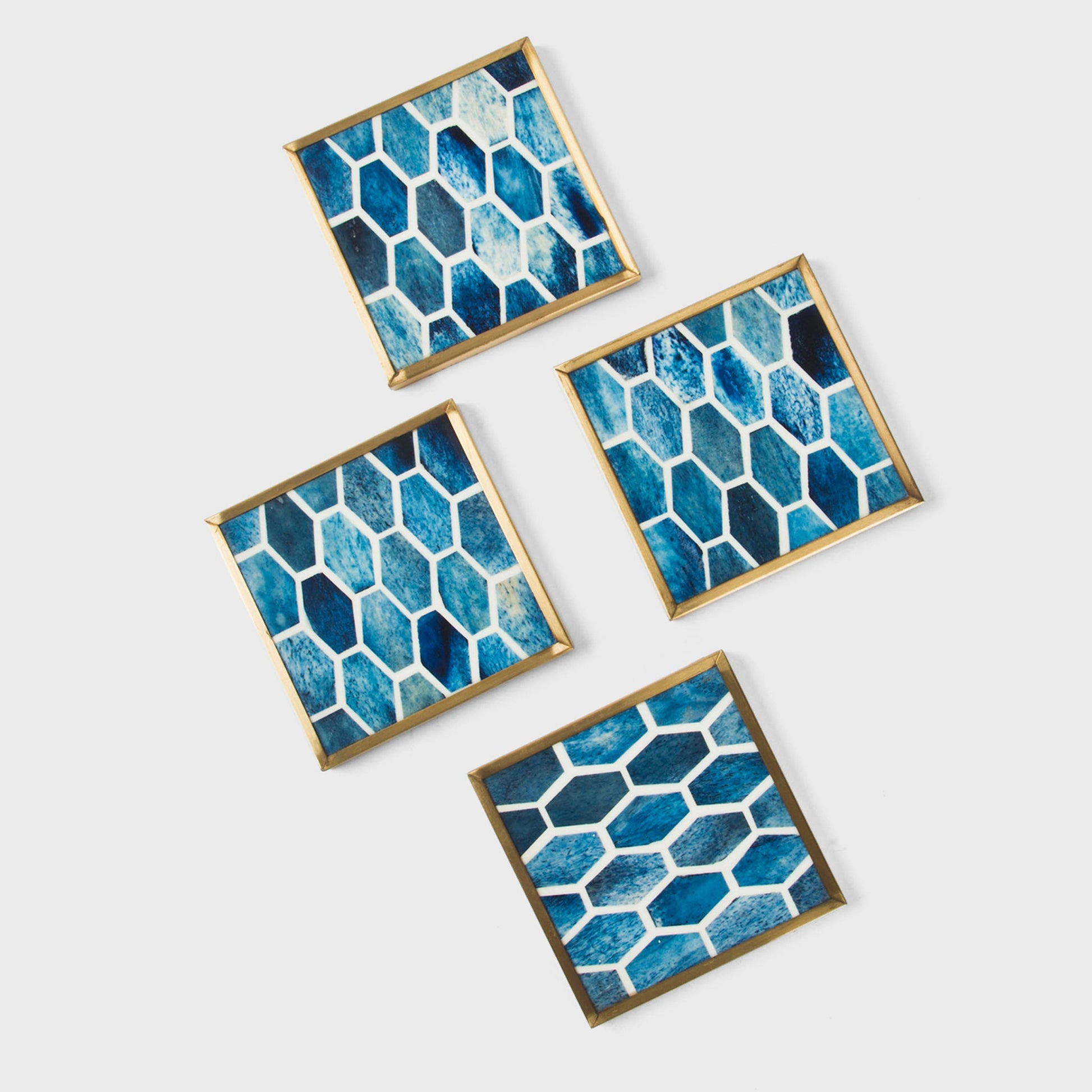 Hand-finished blue geometric drink coasters with moisture-resistant resin and brass metal edges.