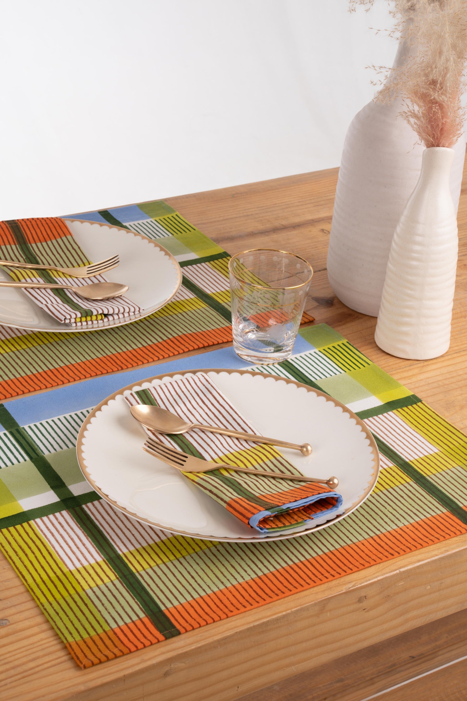 Modernist striped placemats with plates and gold utensils on wooden table