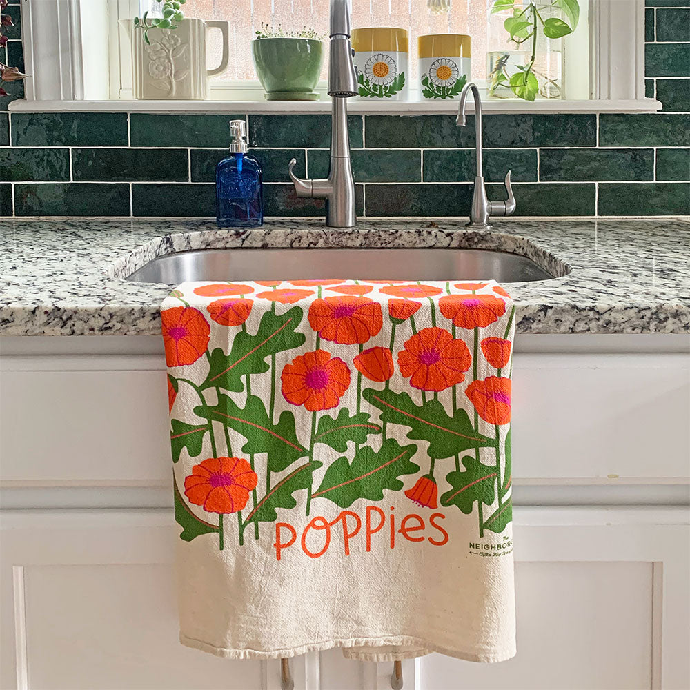 The Neighborgoods Poppies dish towel hanging over kitchen sink faucet displaying poppy flowers illustration. 