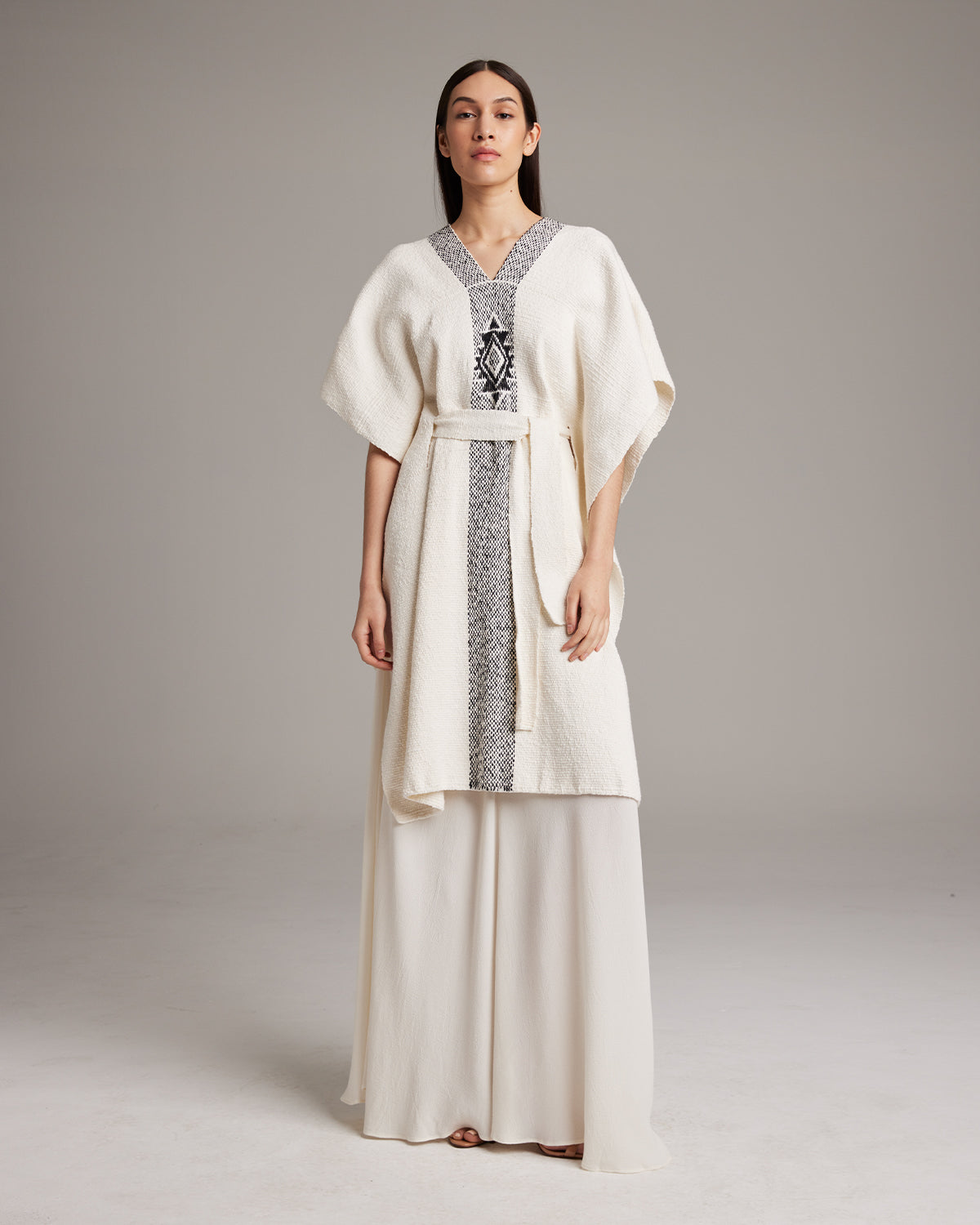 Model wearing a hand-loomed Estrella Kaftan in textured ivory cotton with black detailing