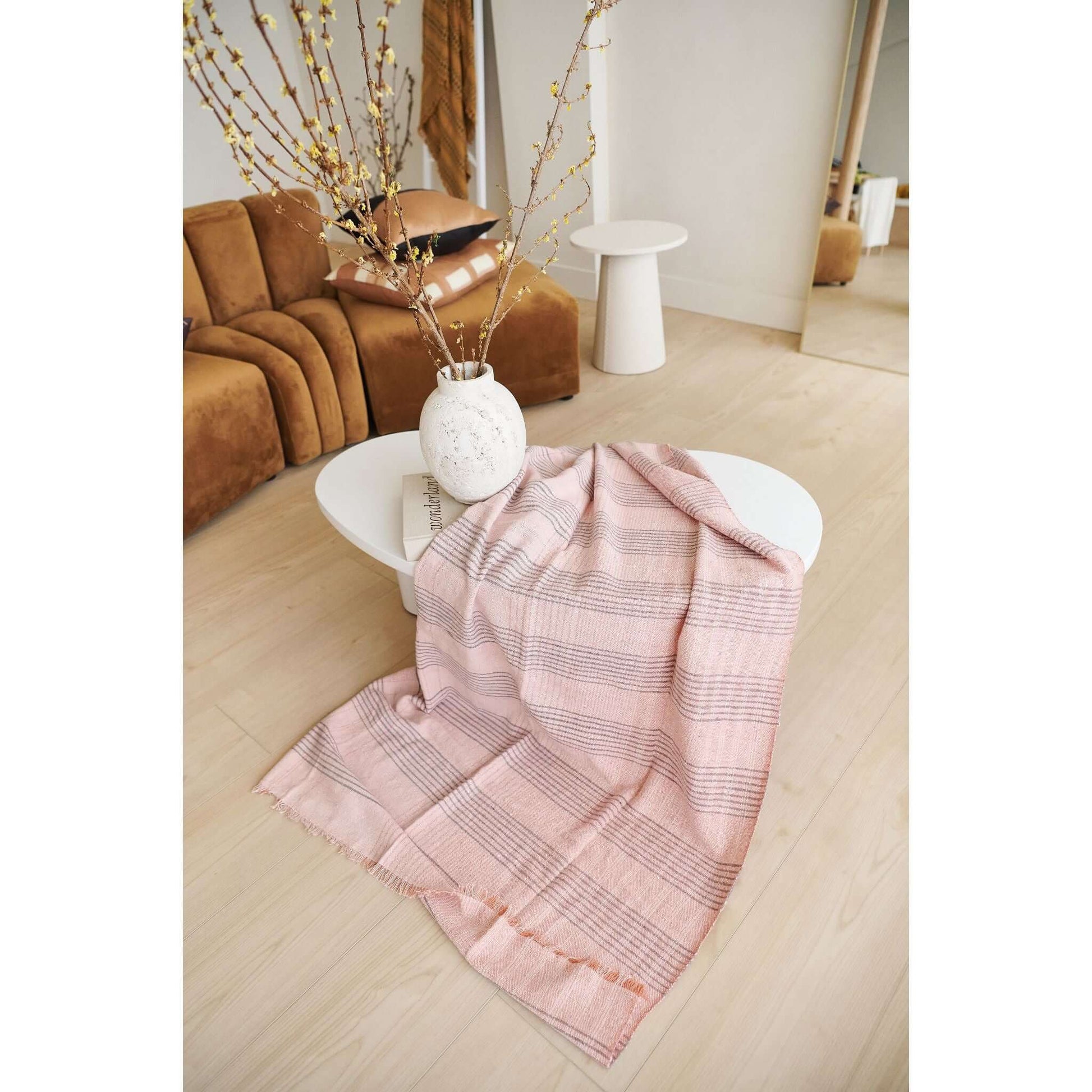 Silica Rose In Shades of Salmon Pink Gray Stripes Pattern Soft Handwoven Merino Throw draped on a modern coffee table.