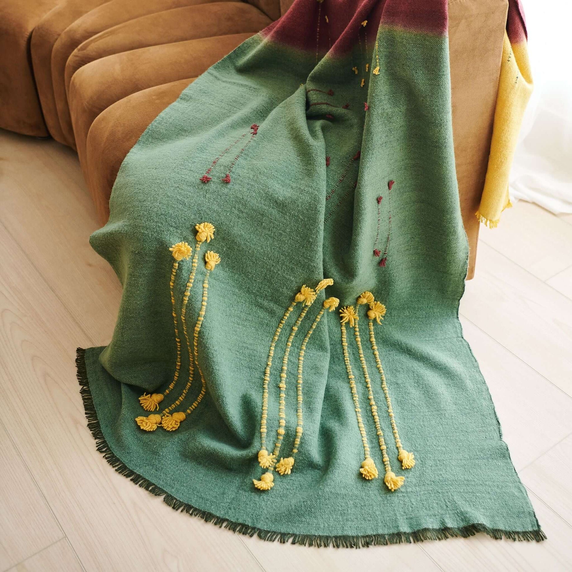 Avocado Green Multi Color Warm Hues Hand Woven Hand Knotted Textured Merino Throw draped over a couch.