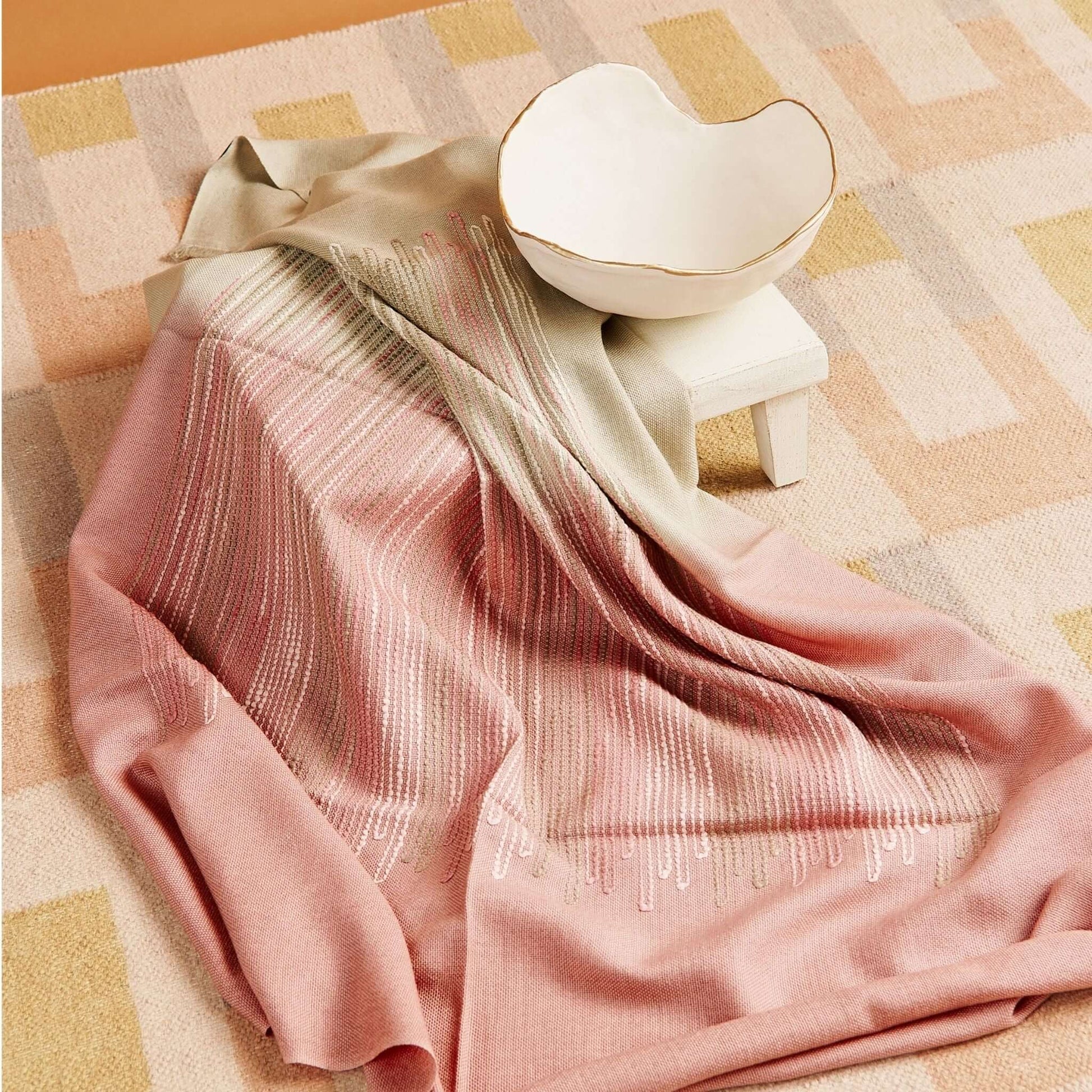 Chive Pink Green Ombre Handloom Merino Throw displayed elegantly with a ceramic bowl on a textured mat.
