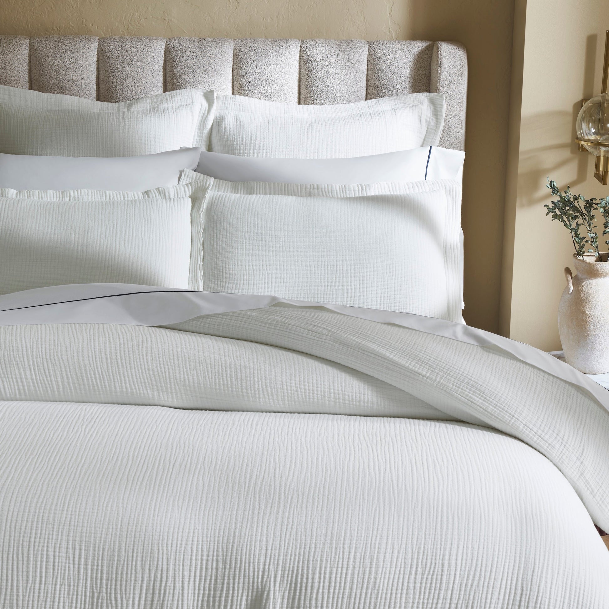 DT-048-10692_3|Close-up of a crisp white textured duvet cover and pillow shams, highlighting the subtle fabric detail and clean, soft bedding.