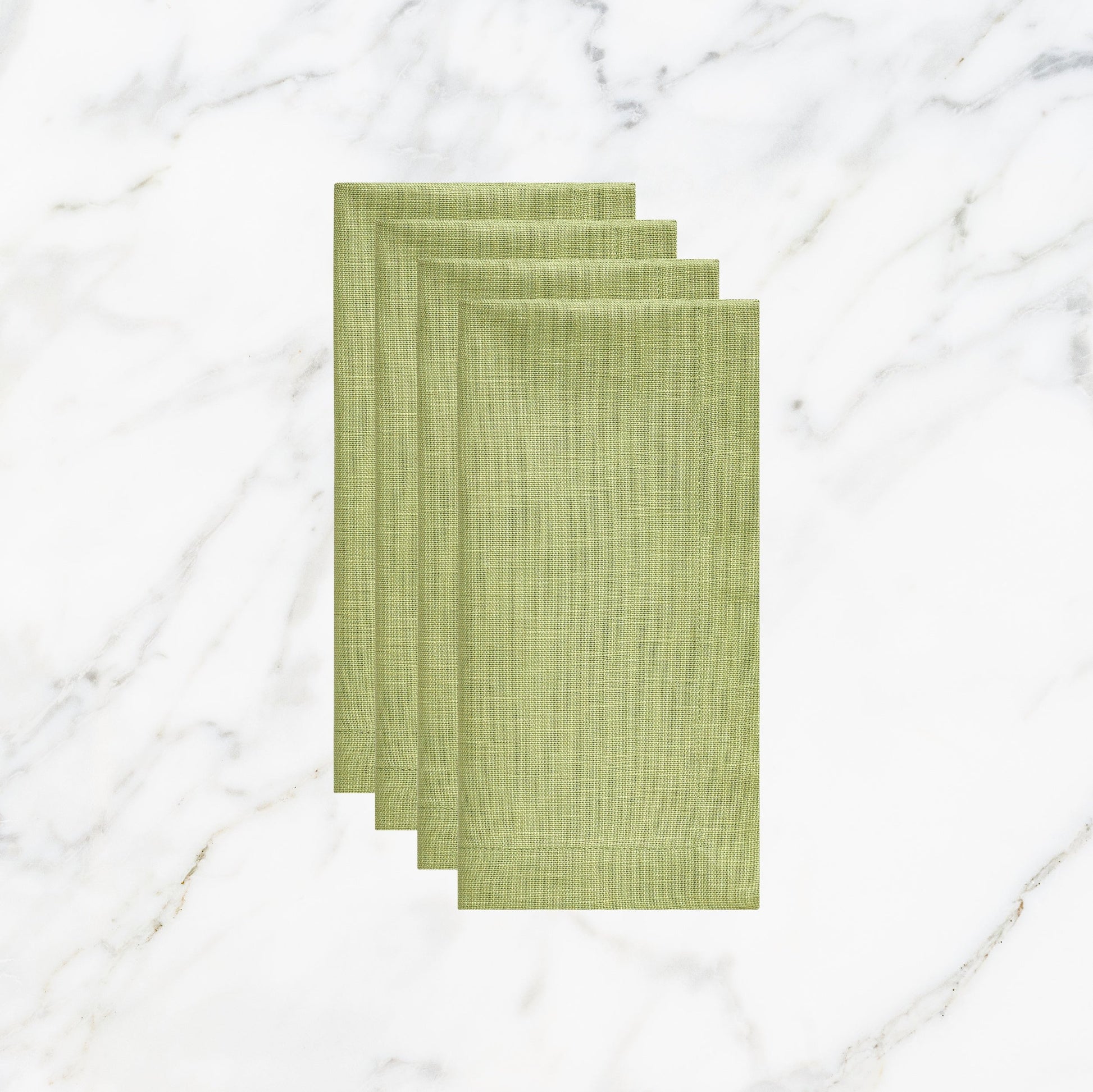 NP-4805-2020_1|Four folded lime green linen-look napkins, elegant table setting accessories on a white marble background. Durable fabric.