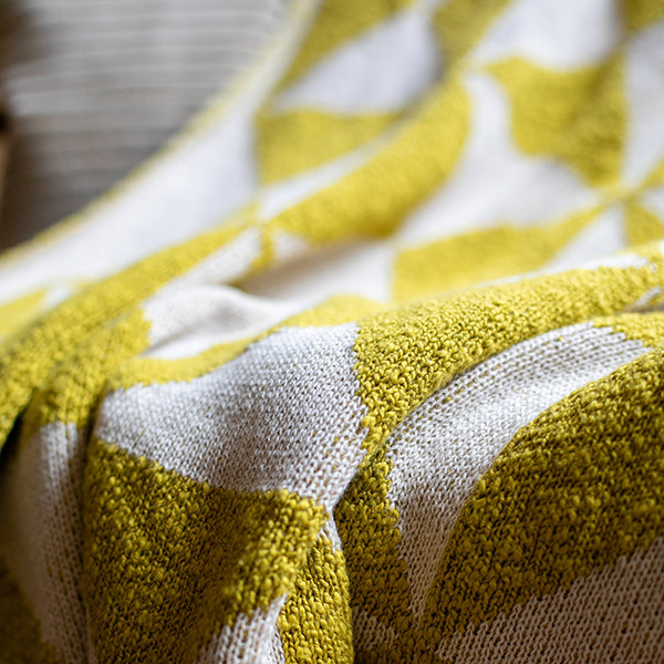 Close-up of a bush green and white patterned organic cotton throw.