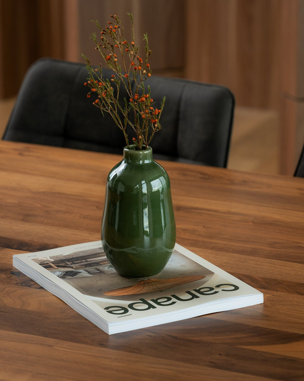 A white stoneware vase with a minimalistic design, placed on a surface and containing a green plant, showcasing its use as a decorative table accessory.