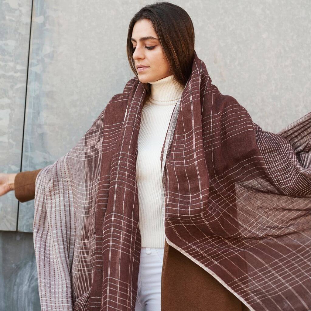 Auro Cinnabar Handwoven Earthy Rust Maroon Linen Scarf draped elegantly over a model wearing a white turtleneck.