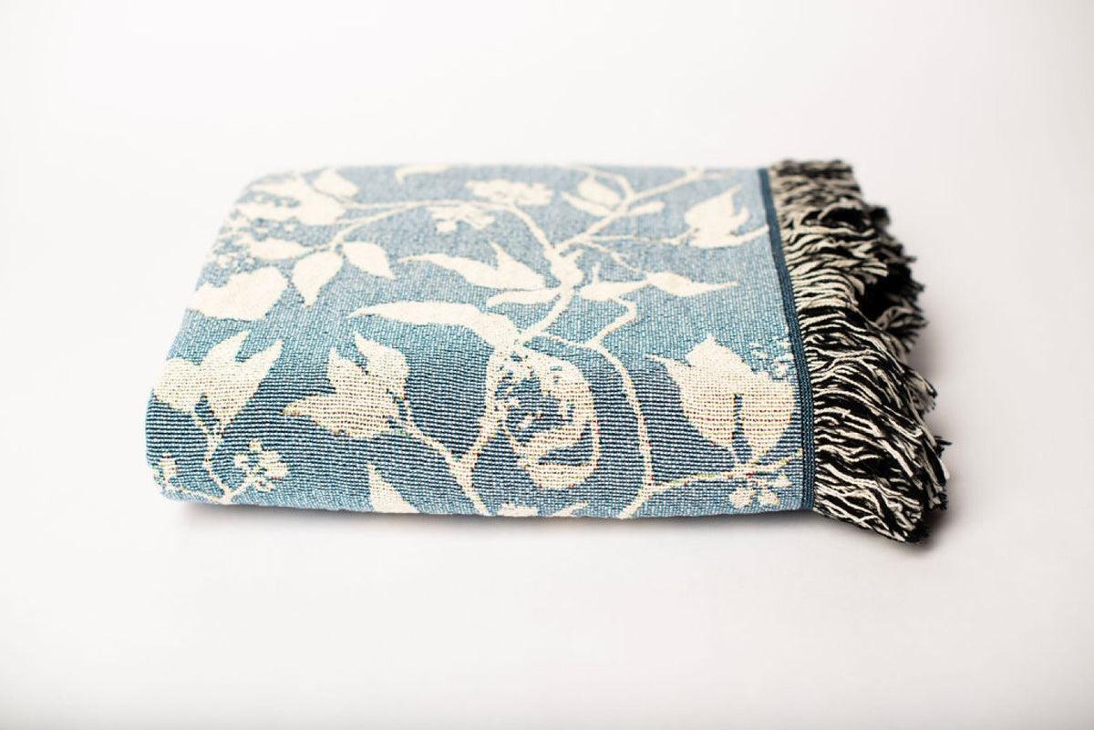 Close-up of Wren Chambray blue and cream bird and botanical woven cotton throw with fringe