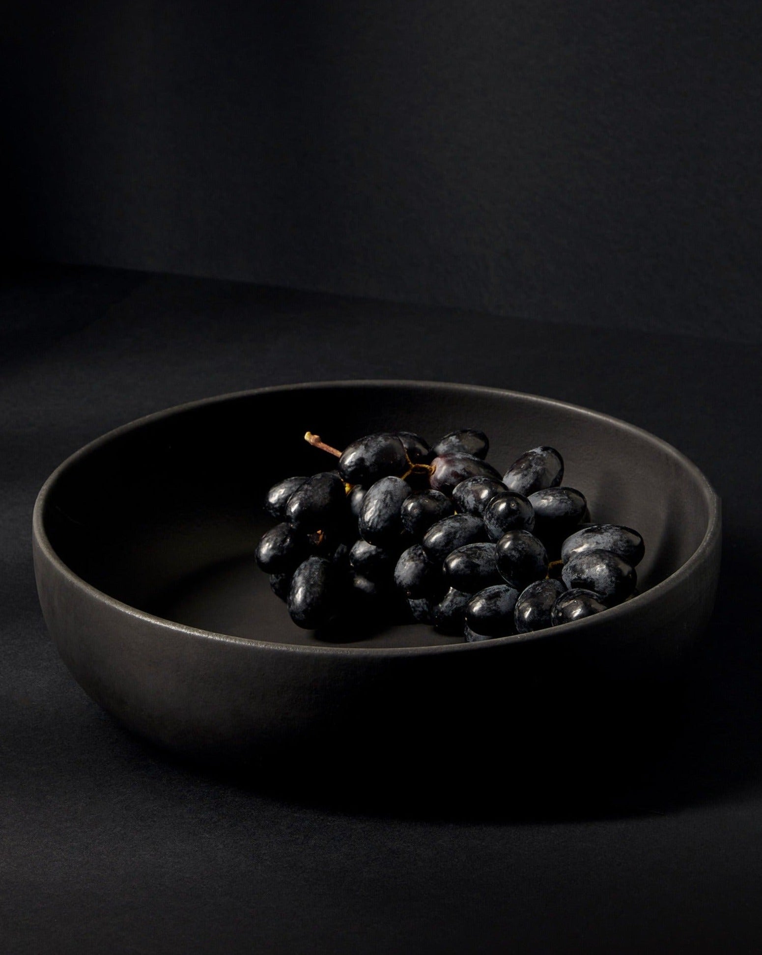 A beige Stoneware Shallow Serving Bowl with a capacity of 60 oz, displayed against a neutral background with a small amount of food items like pasta or noodles in it to showcase its size and shape.