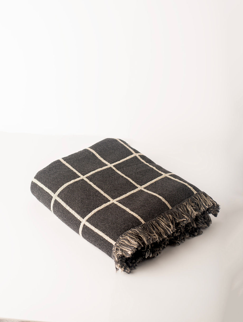 Folded Greer Nocturne charcoal grid woven throw blanket shown from the side