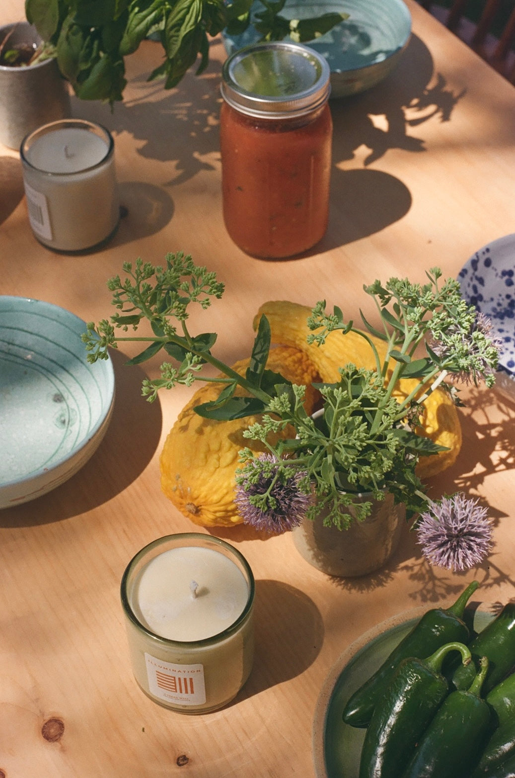 Candle, jars, and plants on a wooden table