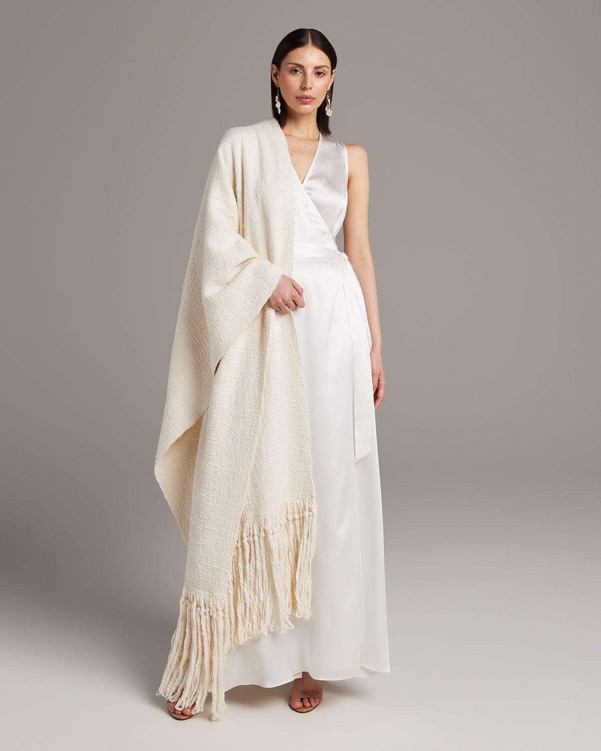 Model wearing a Flammé Fringe Wrap in ivory, showcasing its texture and design.